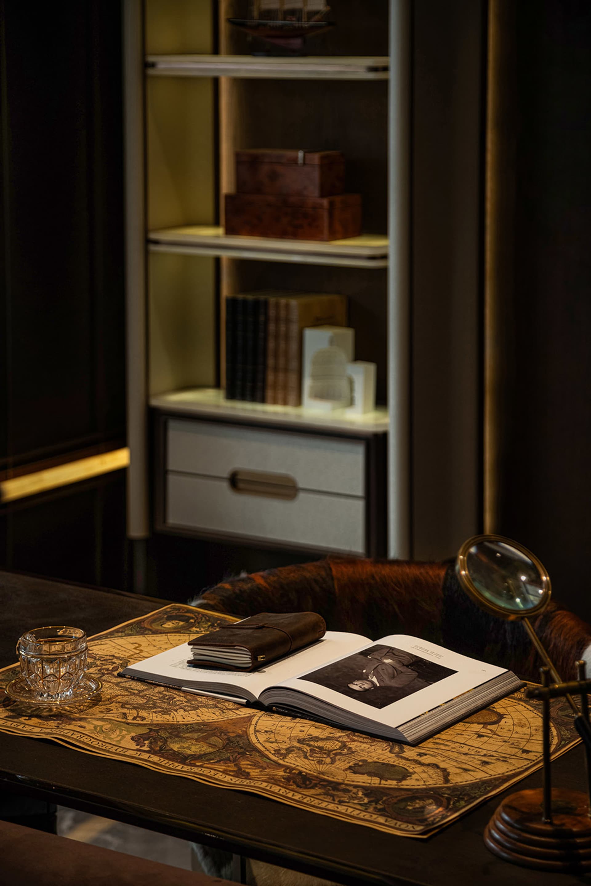 A well-organized bookshelf with a wooden bookcase, books, a cup, a vase, and a clock, creating a cozy and inviting living space atmosphere