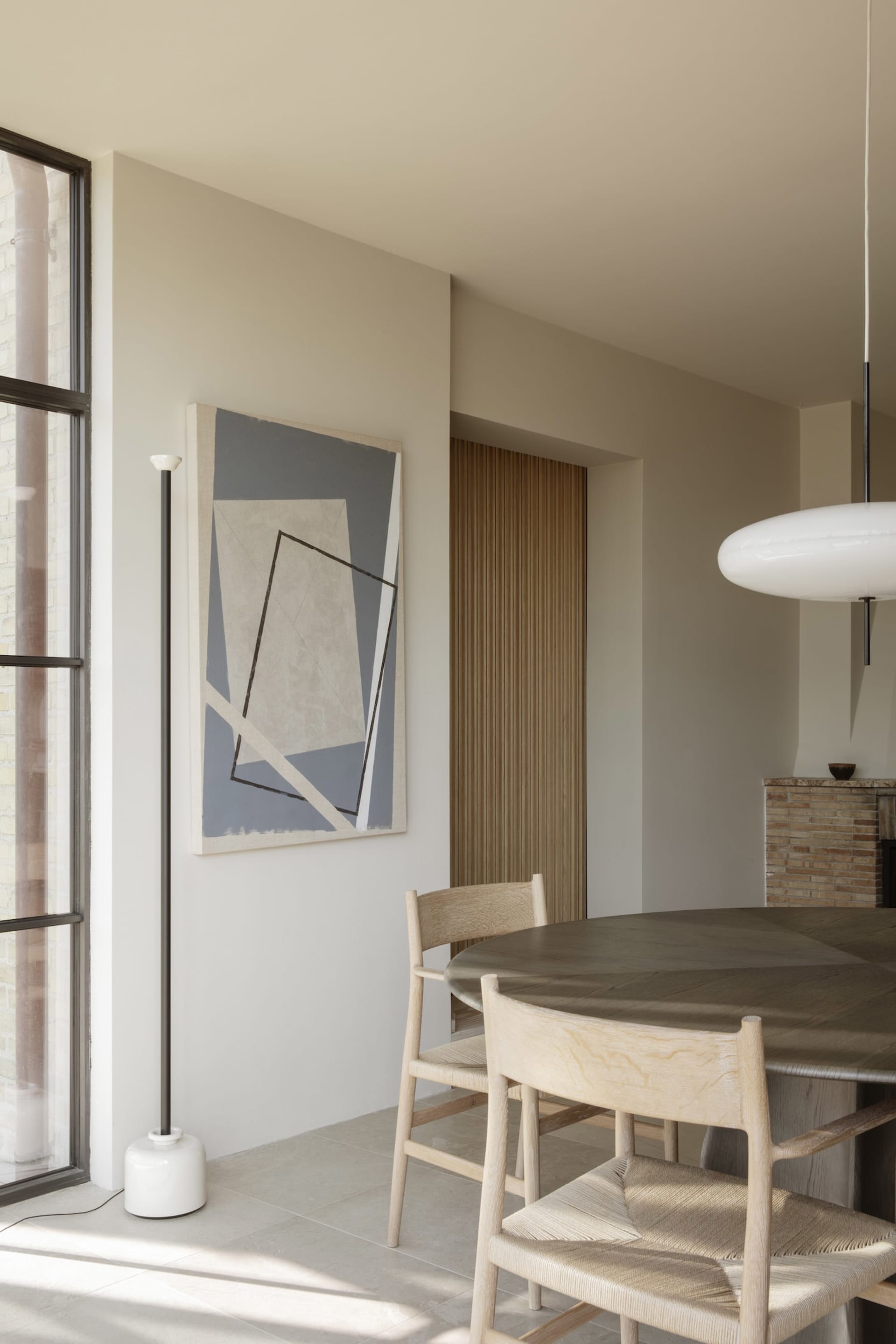 A minimalist dining area with a wooden table and chairs, surrounded by a clean and empty space with soft, diffused lighting