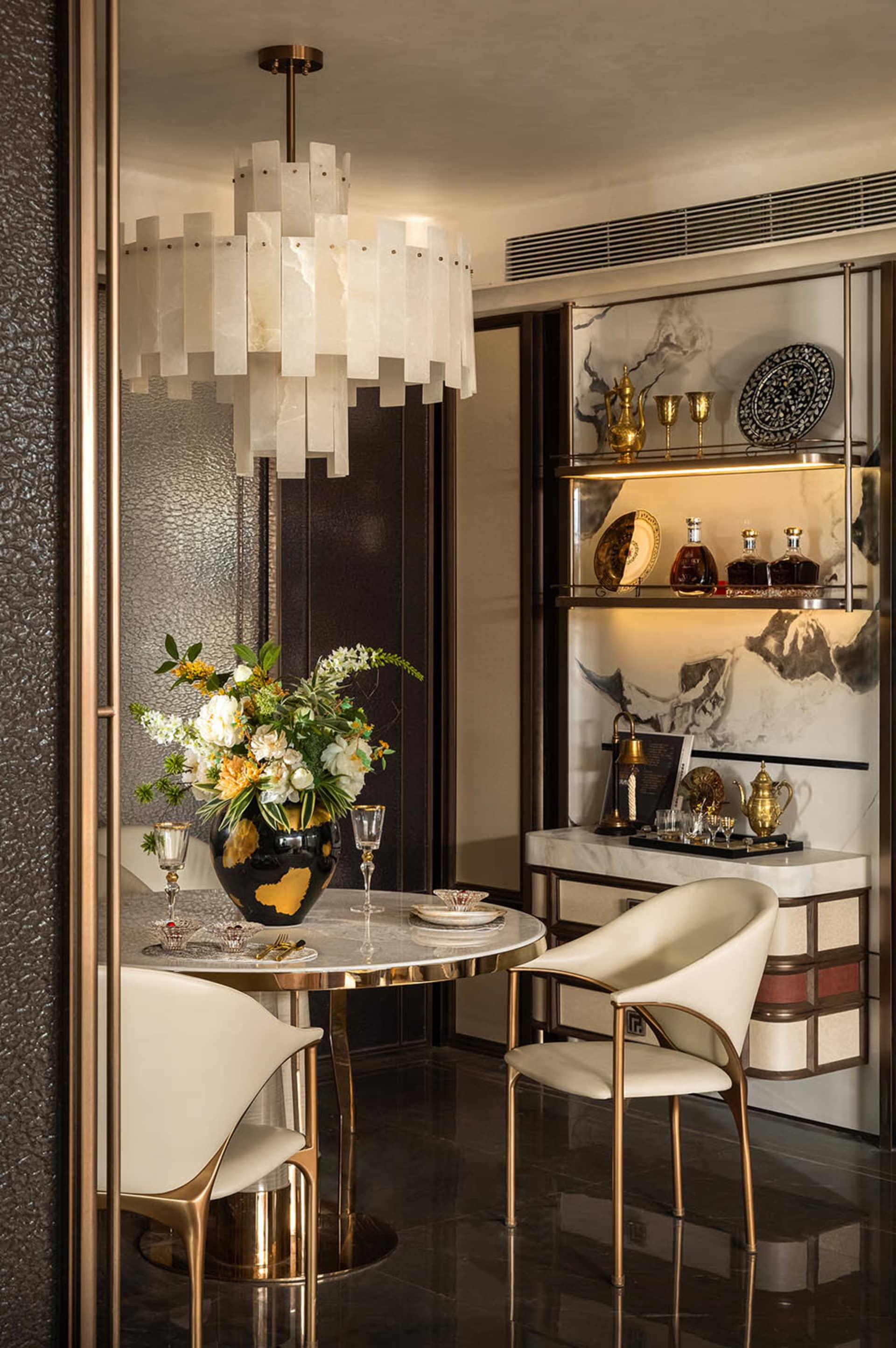 Dining area with a round table, chairs, a vase with flowers, and wine glasses, creating a luxurious and inviting atmosphere
