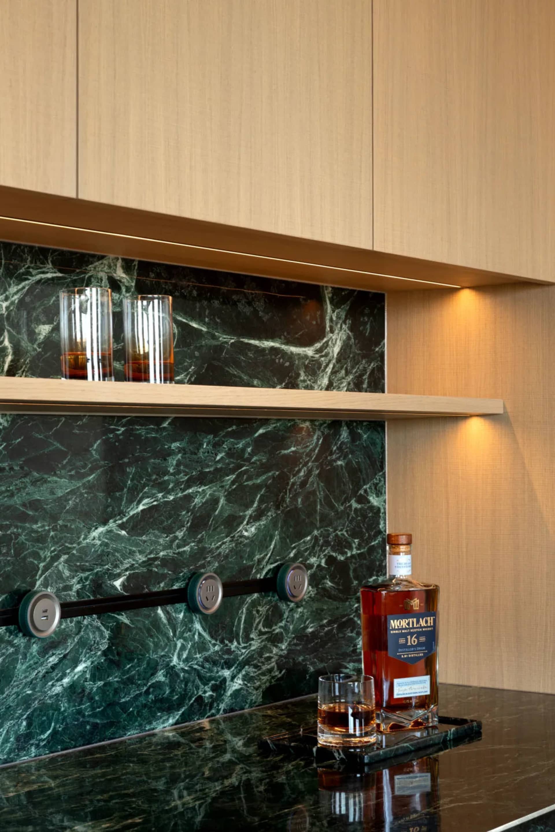 A kitchen with a marble countertop, whiskey bottle, and two wine glasses, creating an elegant and sophisticated atmosphere
