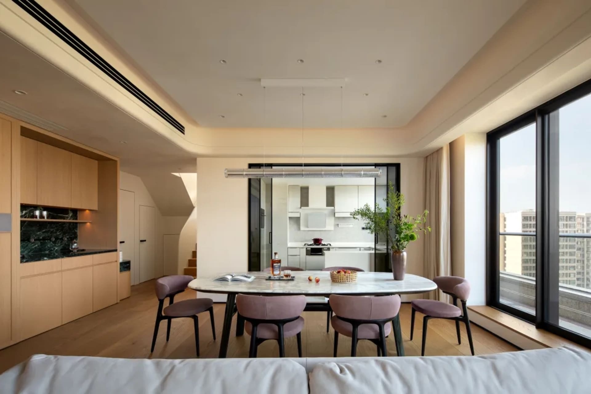 Open living area with kitchen, dining table, chairs, and potted plant, featuring a bright and inviting atmosphere with a focus on functionality and comfort