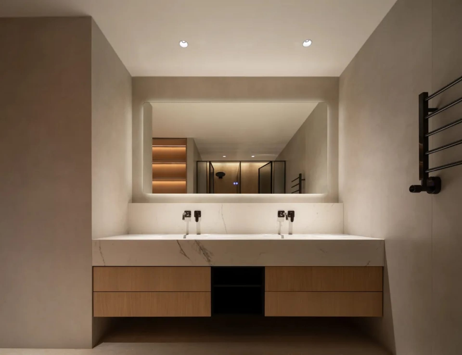 Bathroom with a large marble sink, two faucets, two mirrors, and a wooden cabinet, lit with bright and inviting lighting