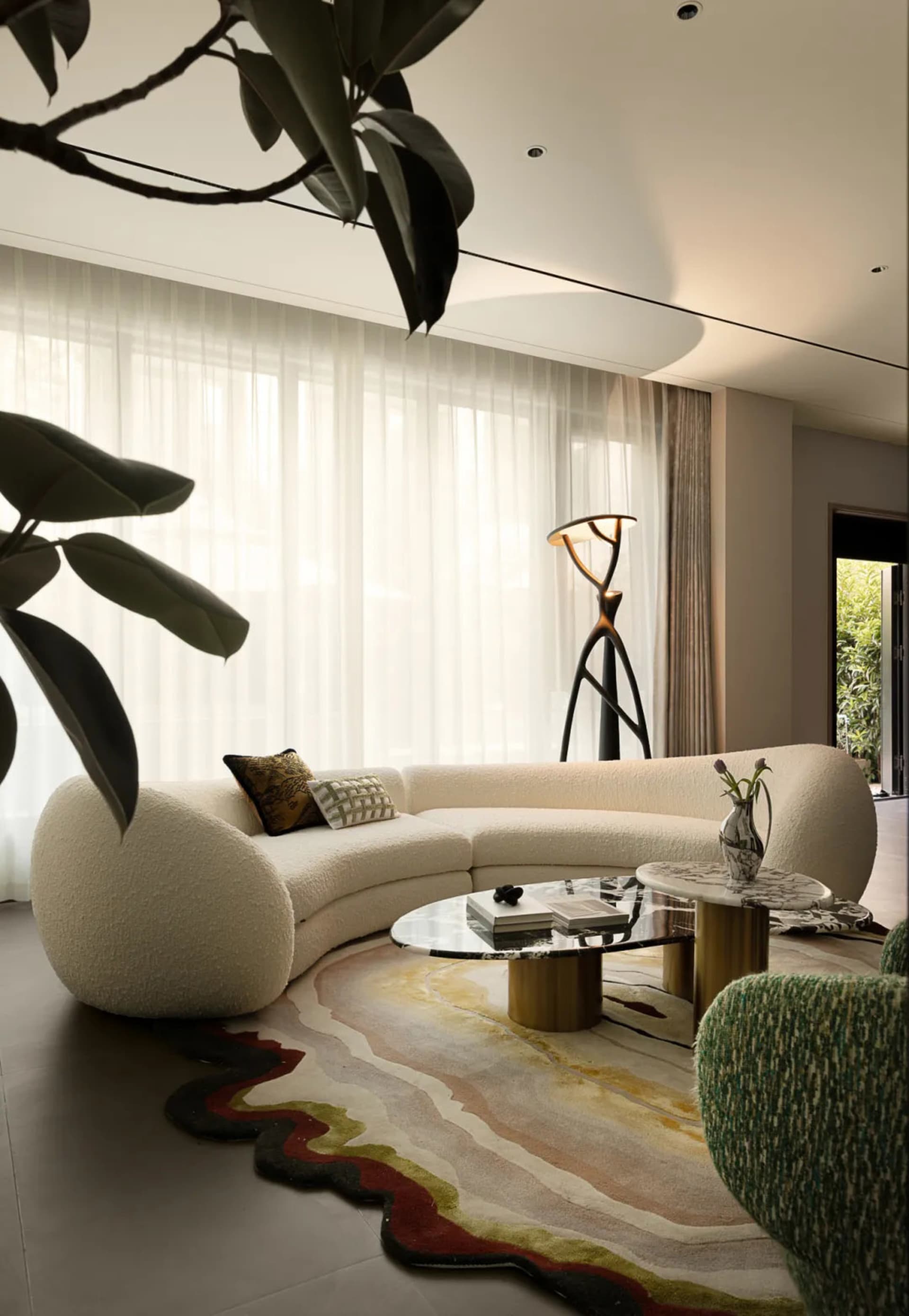Cozy living room with a white couch, potted plants, a vase, and a chair, set against a neutral background