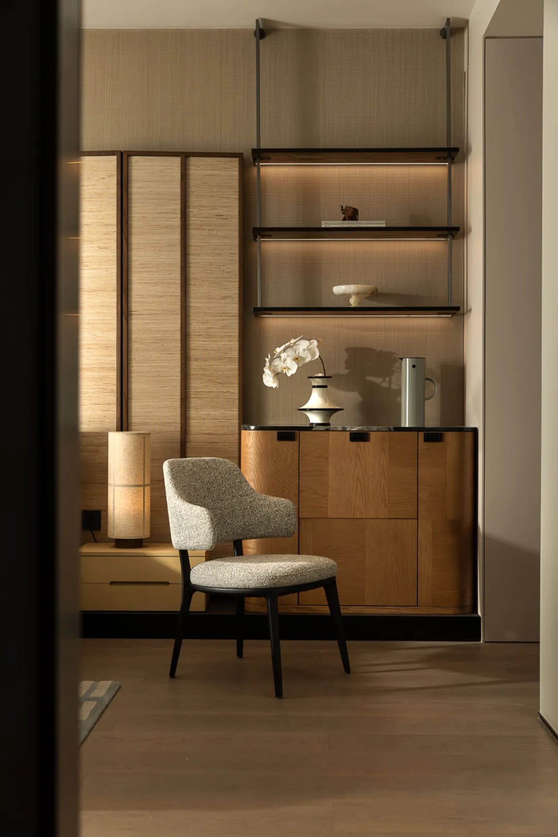 Cozy living space with wooden floors and walls, featuring a bookshelf, two chairs, and a vase, with a warm and inviting atmosphere