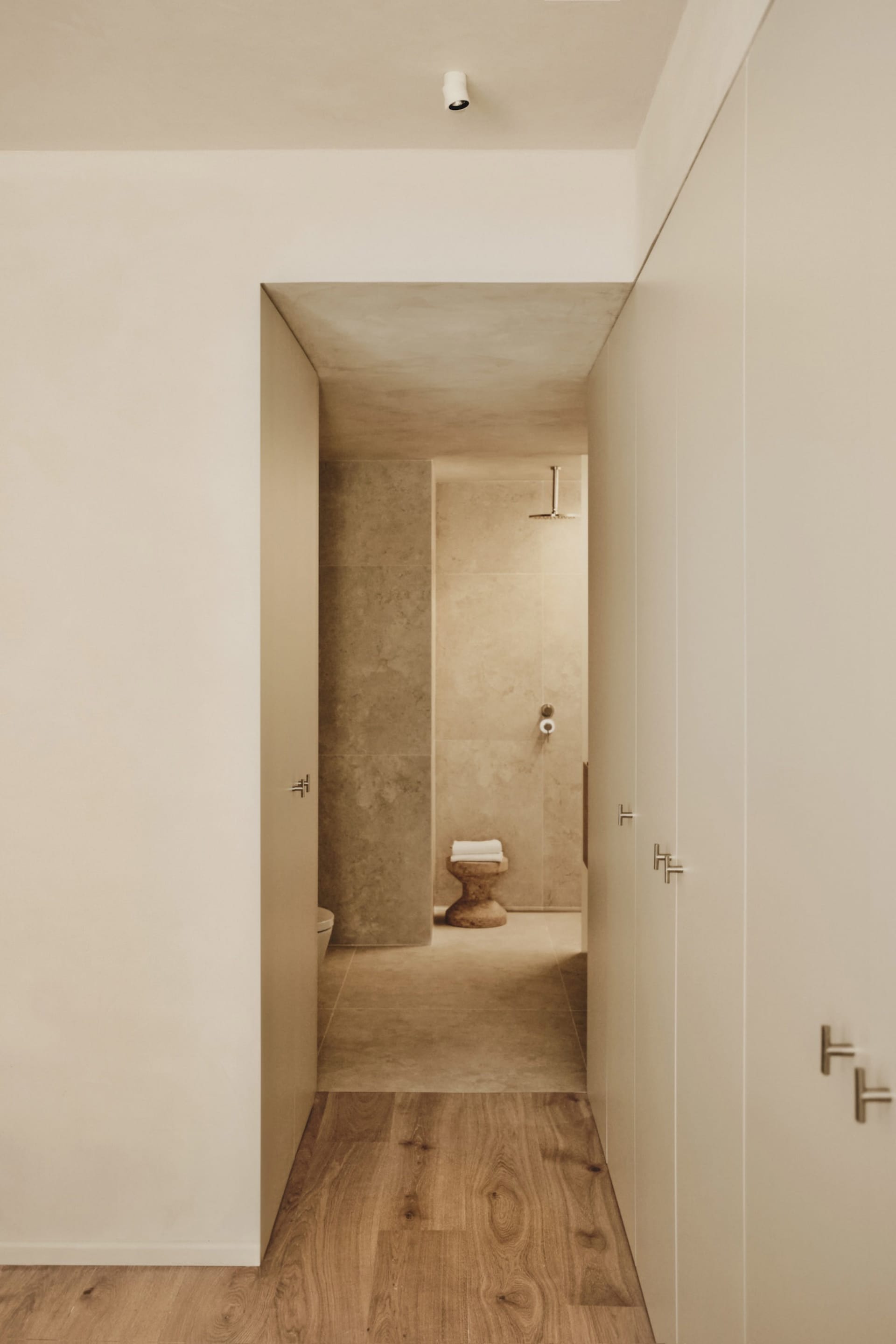 Bathroom with tile walls, a toilet, and two doors, creating a calm and inviting atmosphere