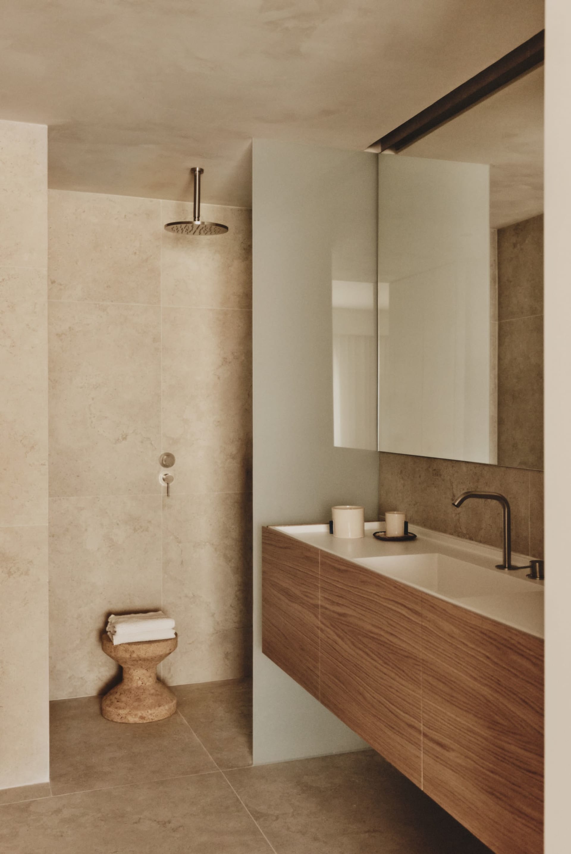 Modern bathroom with a sink, mirror, shower, and toilet, featuring clean lines and minimalistic elements