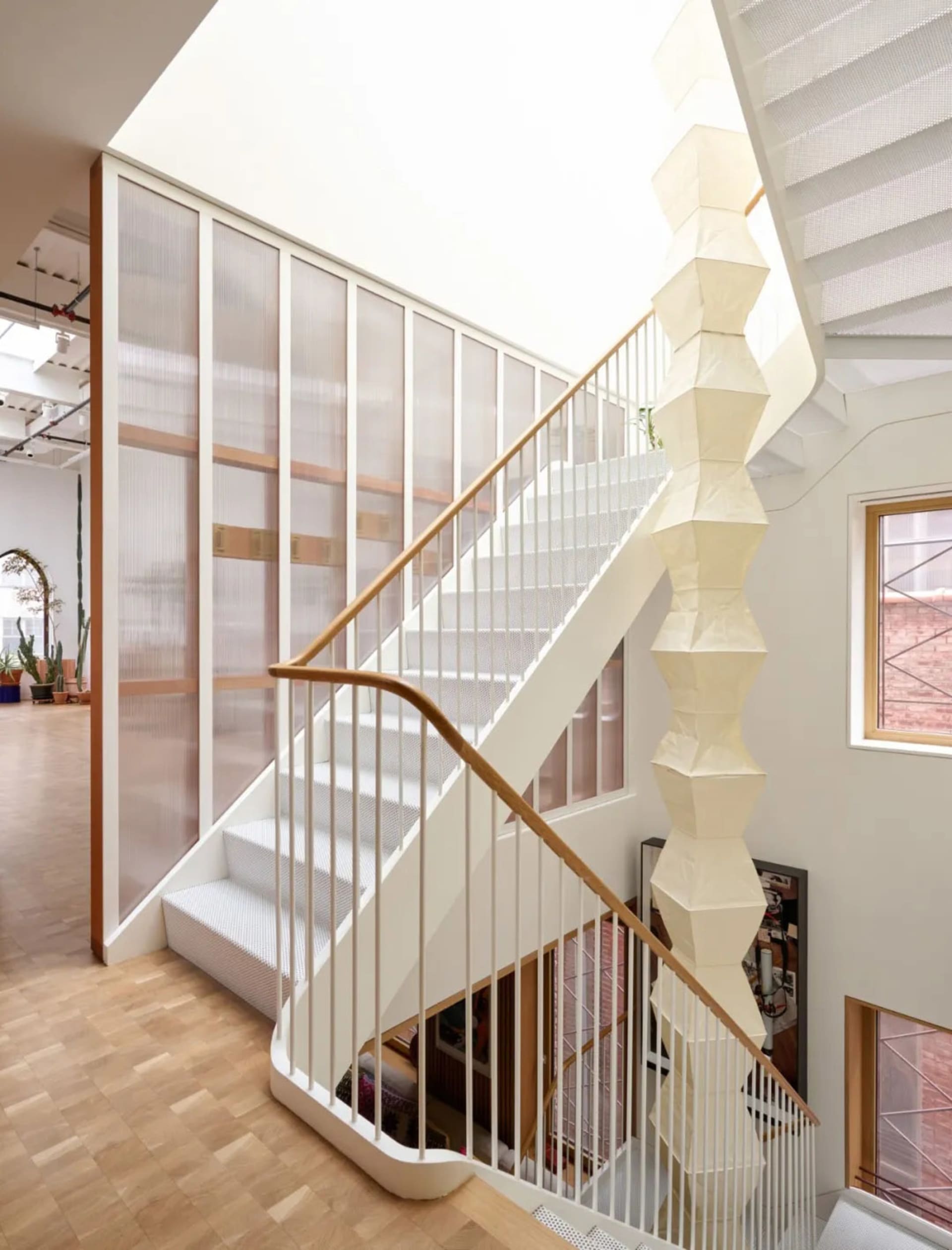 Modern staircase with wooden steps and white railing, surrounded by natural light from two windows on either side