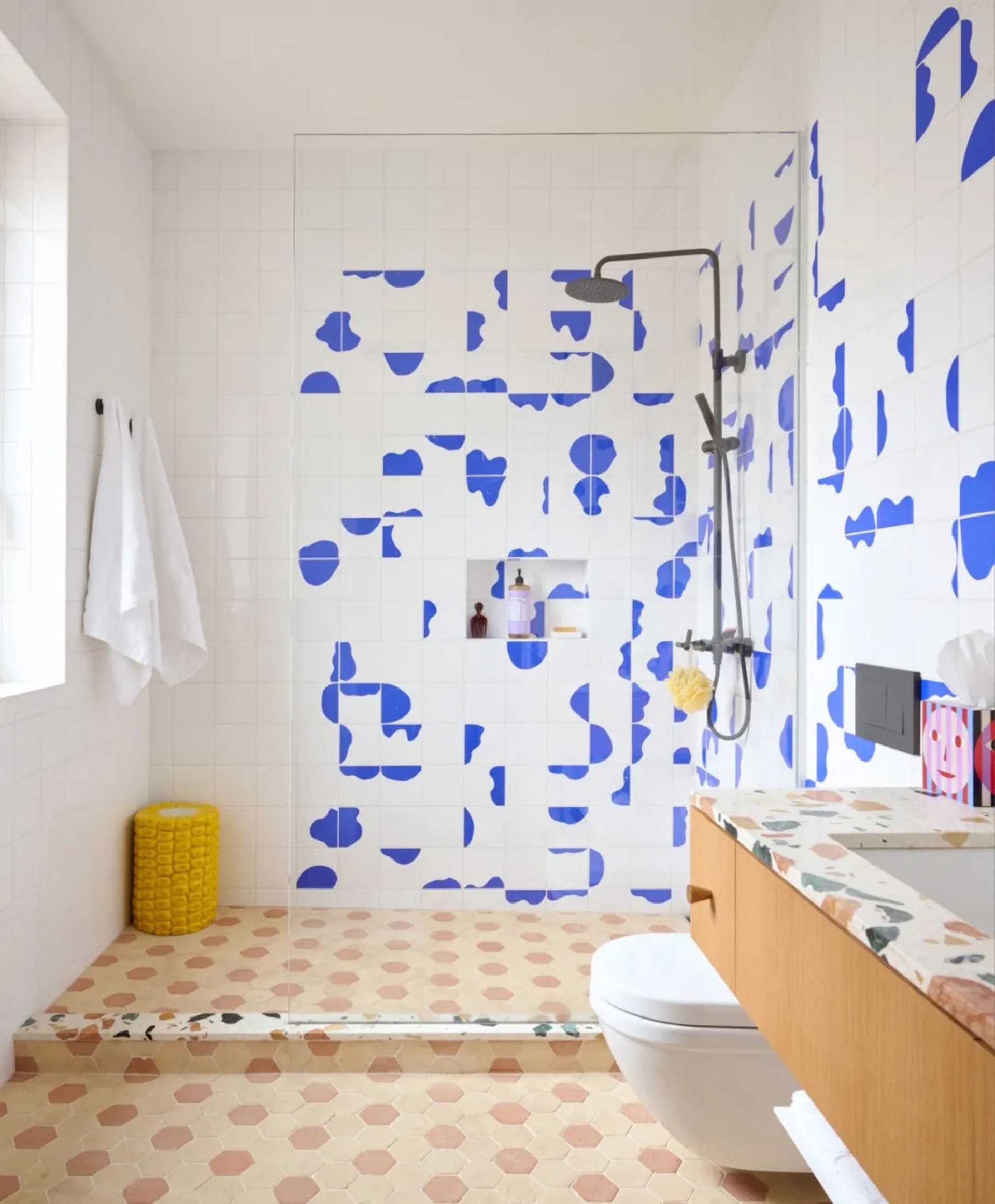 Bathroom with a blue dot pattern on the walls, a yellow basket near the toilet, and a clean and organized atmosphere