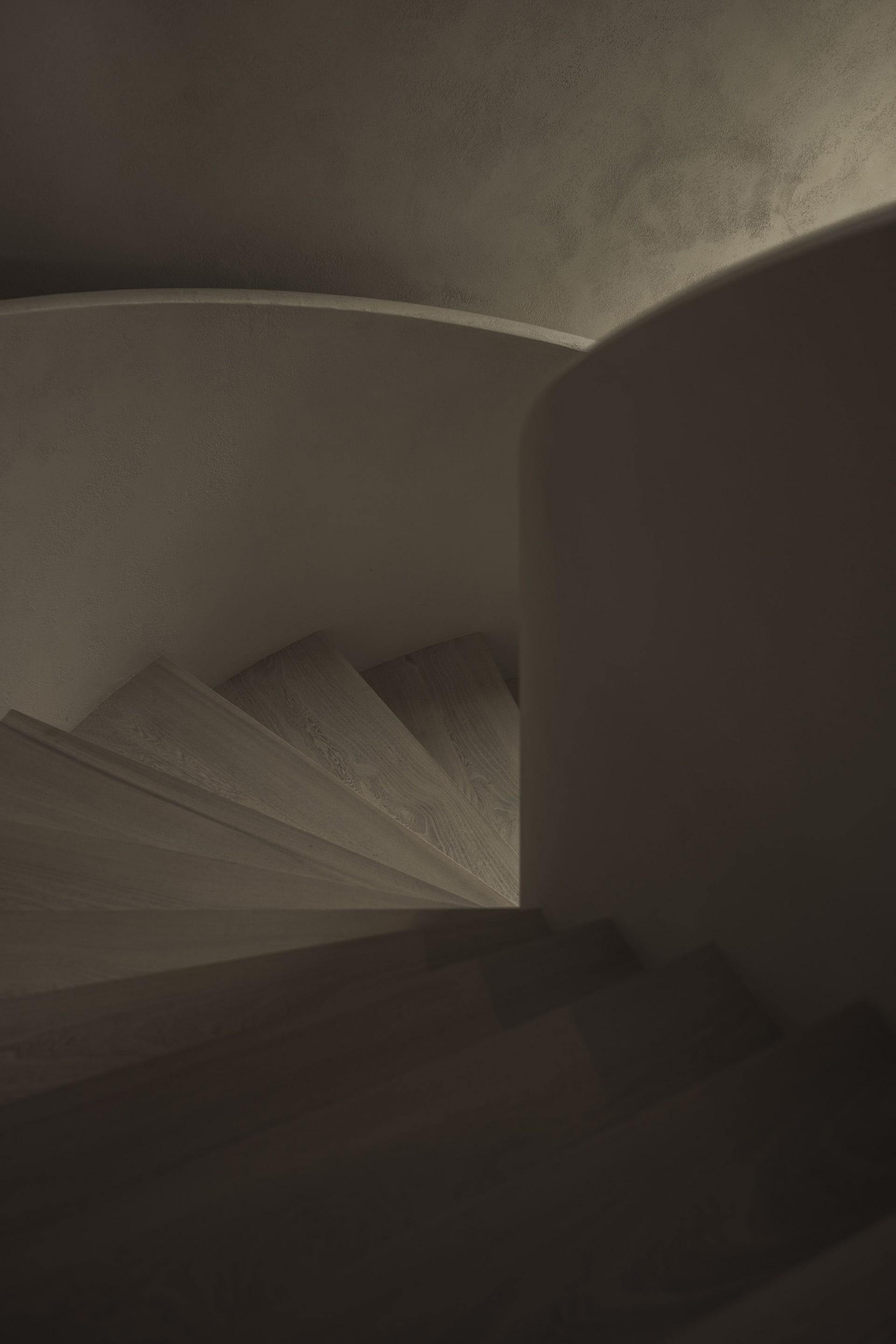 A curved wooden staircase with a railing in a bright, daytime setting