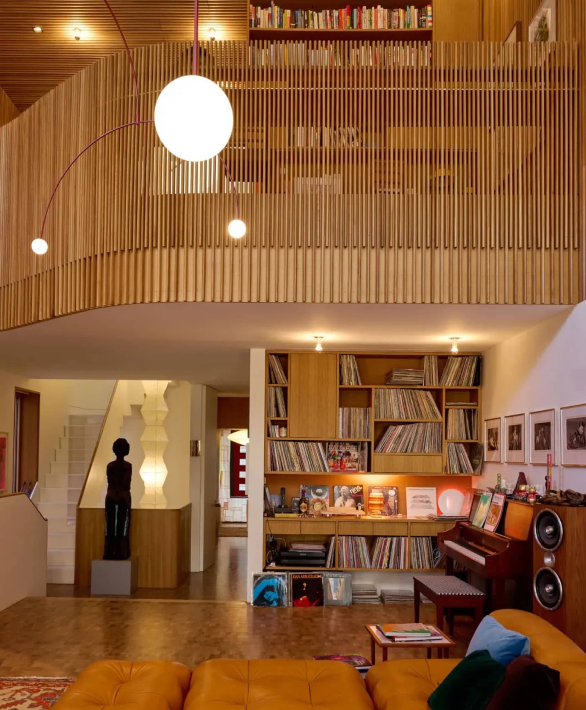 Warm and inviting living space with wooden floors and walls, featuring a piano and scattered books, and a focus on relaxation and entertainment