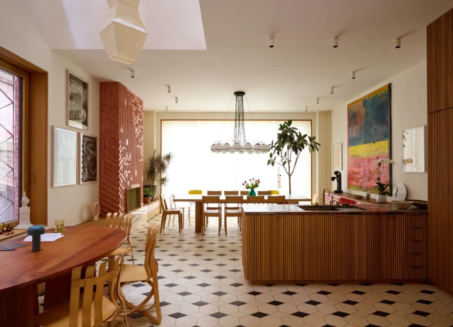 Open living area with a wooden kitchen island, potted plants, a dining table, and a comfortable couch in a bright and inviting space