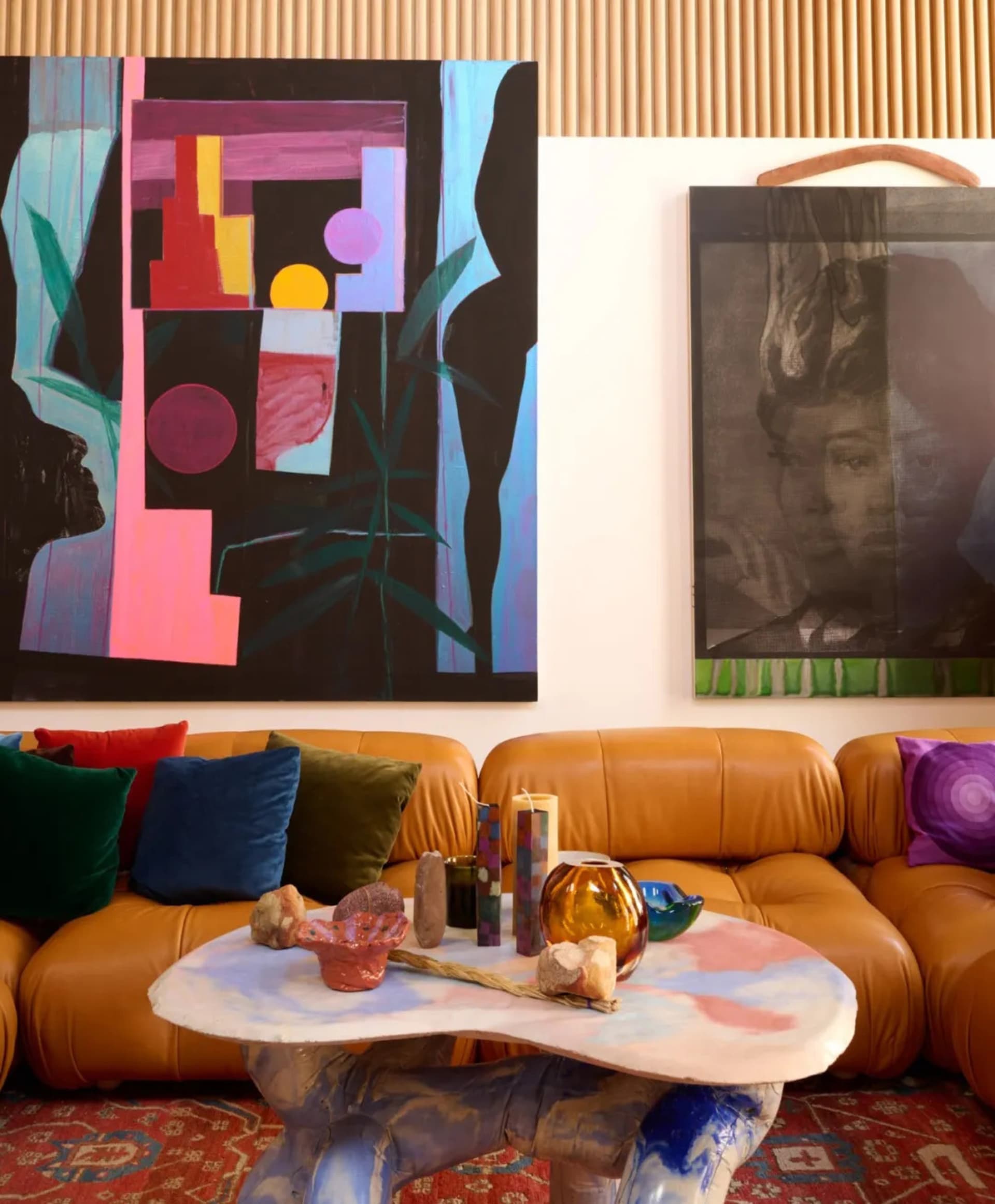 Cozy living room with artwork, a couch, dining table, chair, and decorative pillows, set against a neutral background