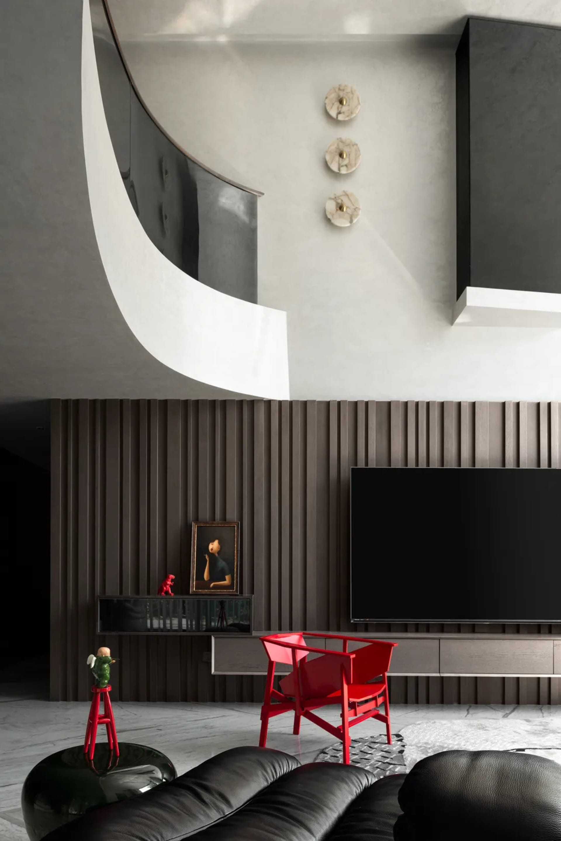 Modern living room with a large flat screen TV, red and black chairs, and a small figurine on a minimalist floor, with a focus on functionality and comfort