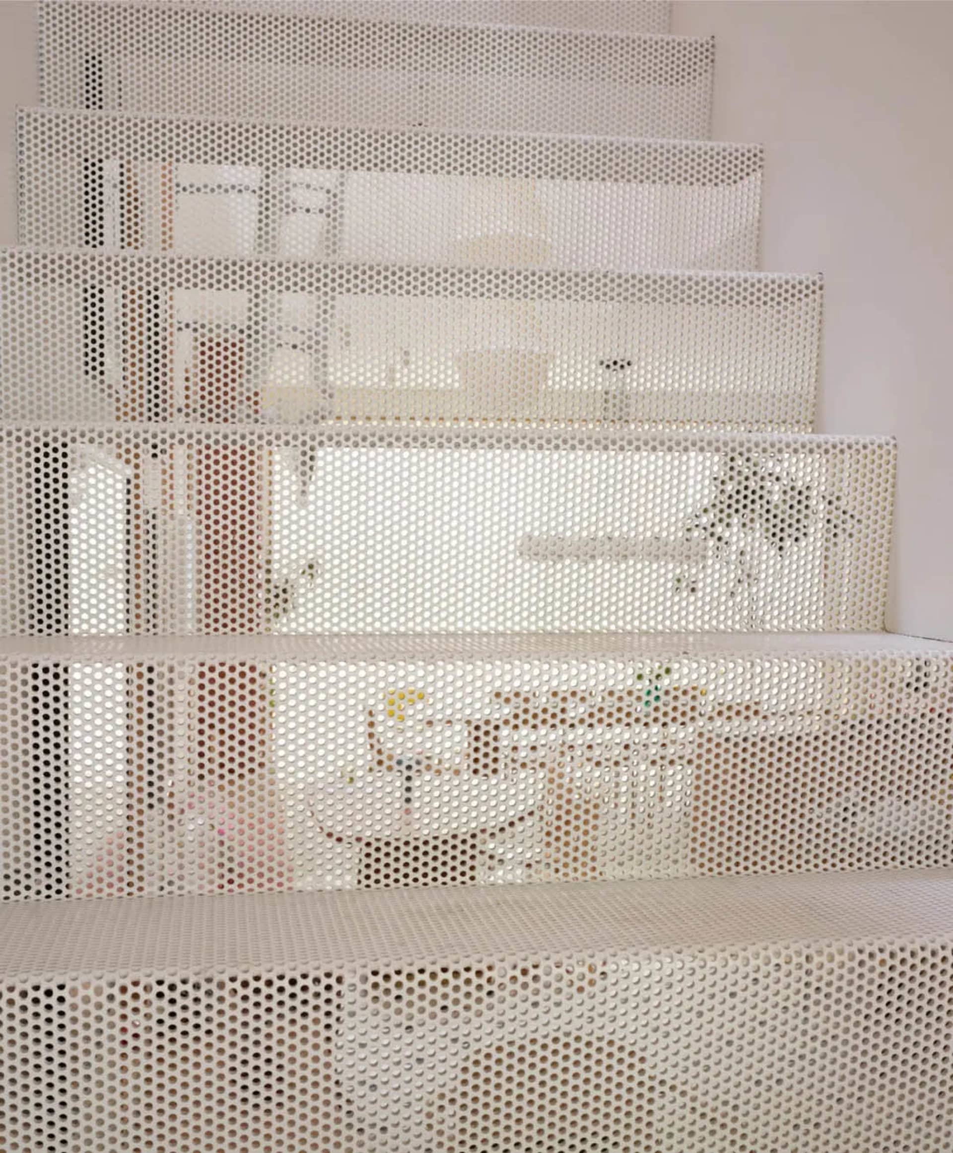 A modern staircase in a white house with a potted plant and two bottles, conveying simplicity and cleanliness