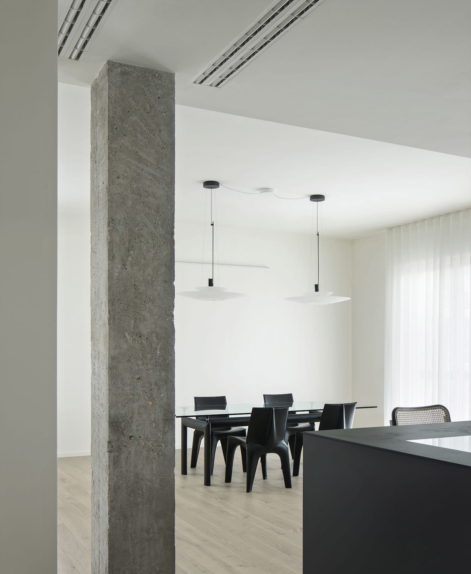 A modern dining space with a large table surrounded by chairs, featuring a white color scheme and a clean appearance