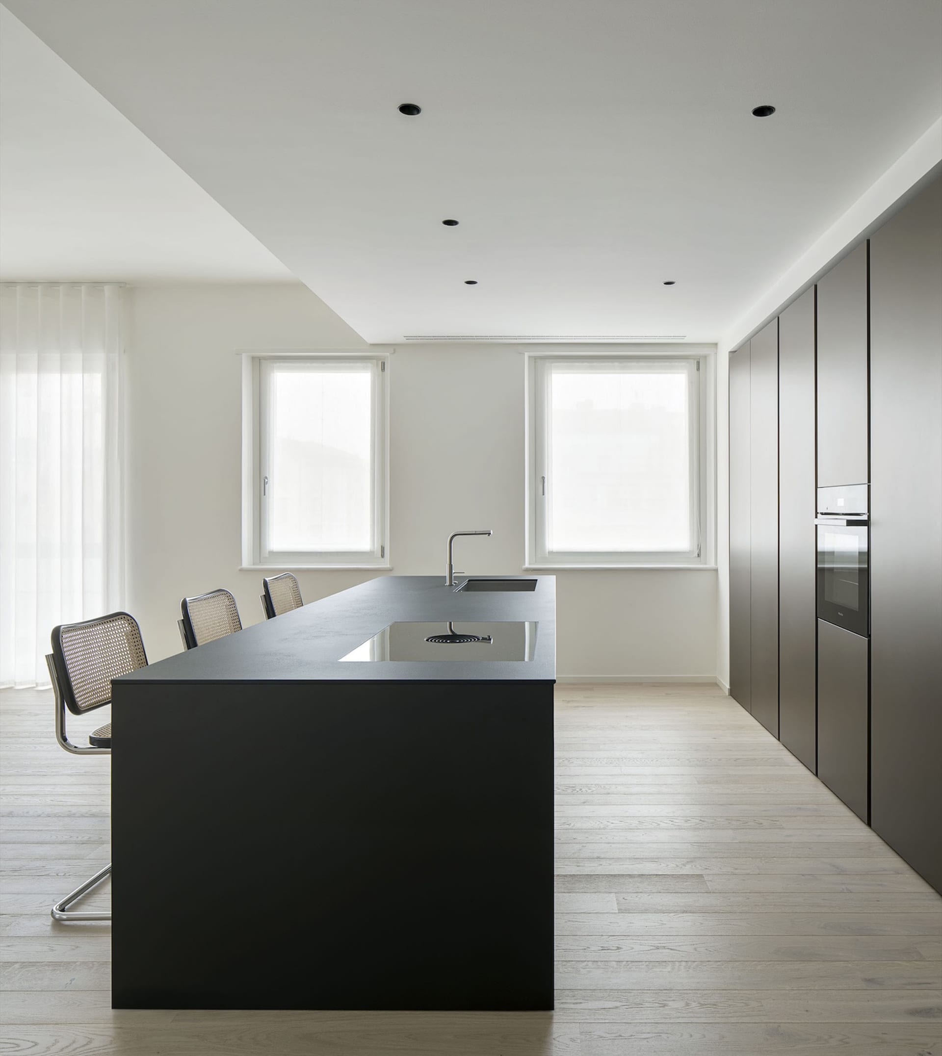 Modern kitchen with black countertops, white walls, wooden floors, and various appliances