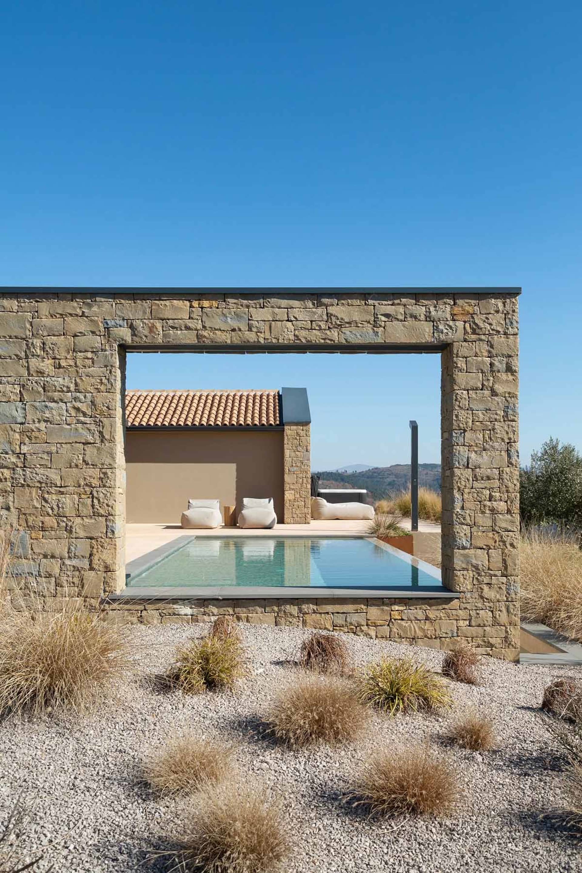 Architectural rendering of a modern house with a stone pool wall, two chairs, and a couch in a relaxing and inviting atmosphere