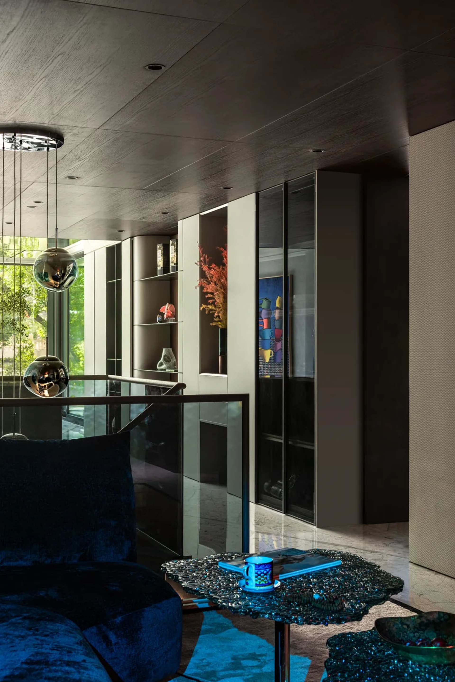 Open living area with glass walls, two couches, a dining table, chairs, and decorative vases, well-lit and inviting