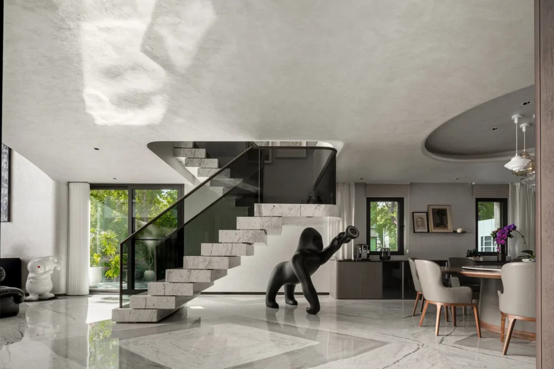 A modern living space with a black monkey statue, two chairs, and decorative vases in a white room