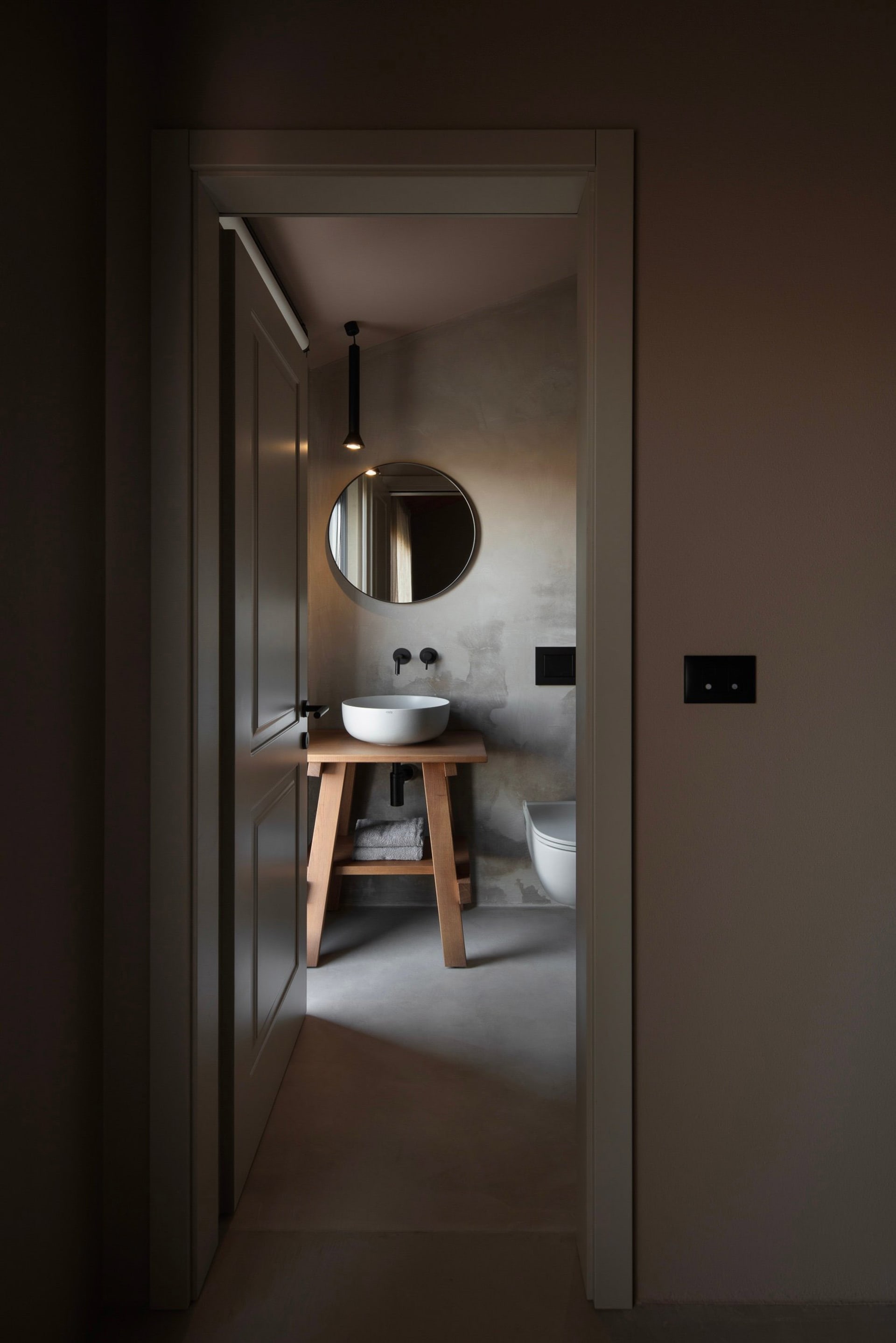 Bathroom with a wooden sink stand, mirror, and toilet, featuring a simple and functional design