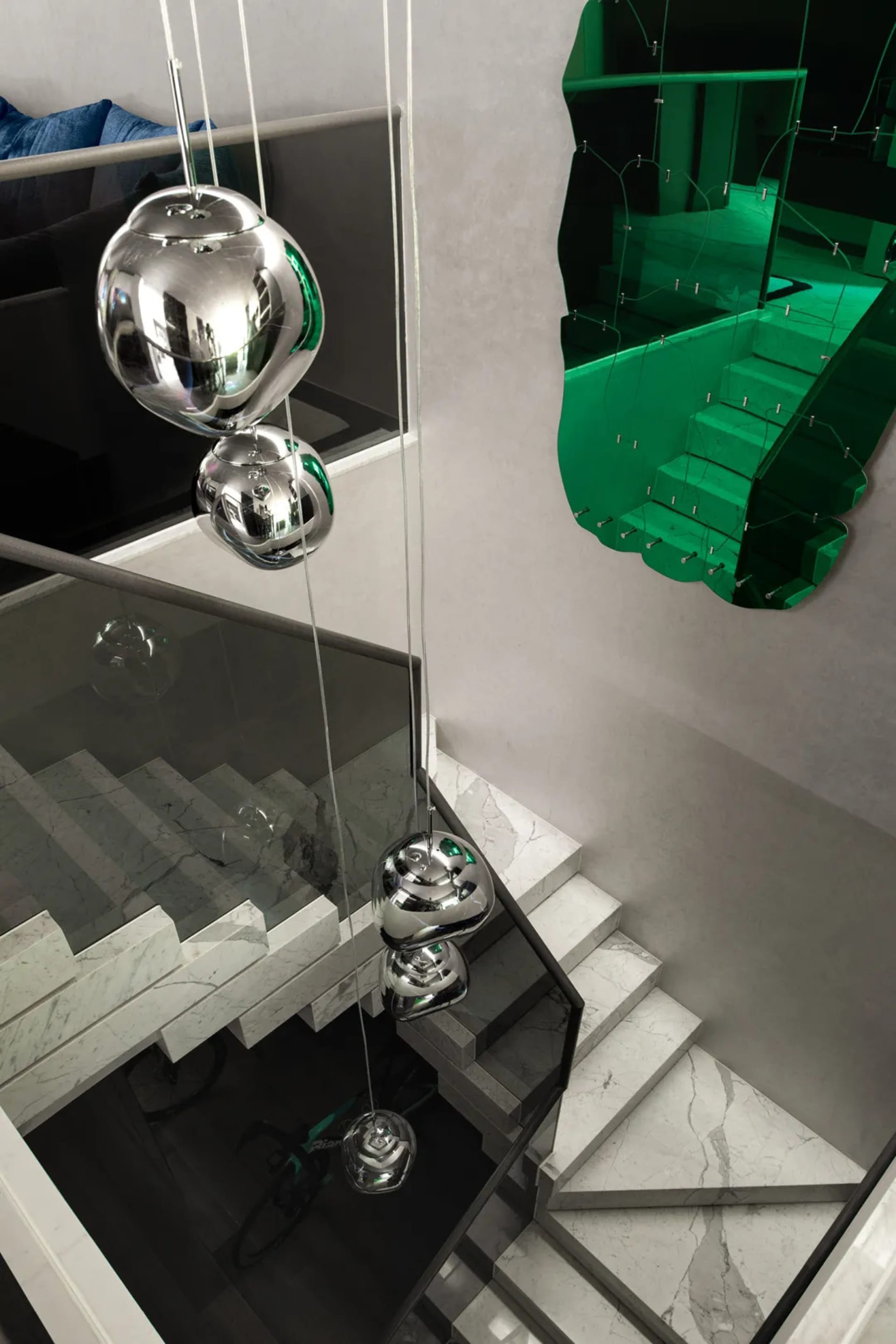 A luxurious staircase with marble steps and a unique installation featuring three large glass or crystal orbs hanging from the ceiling
