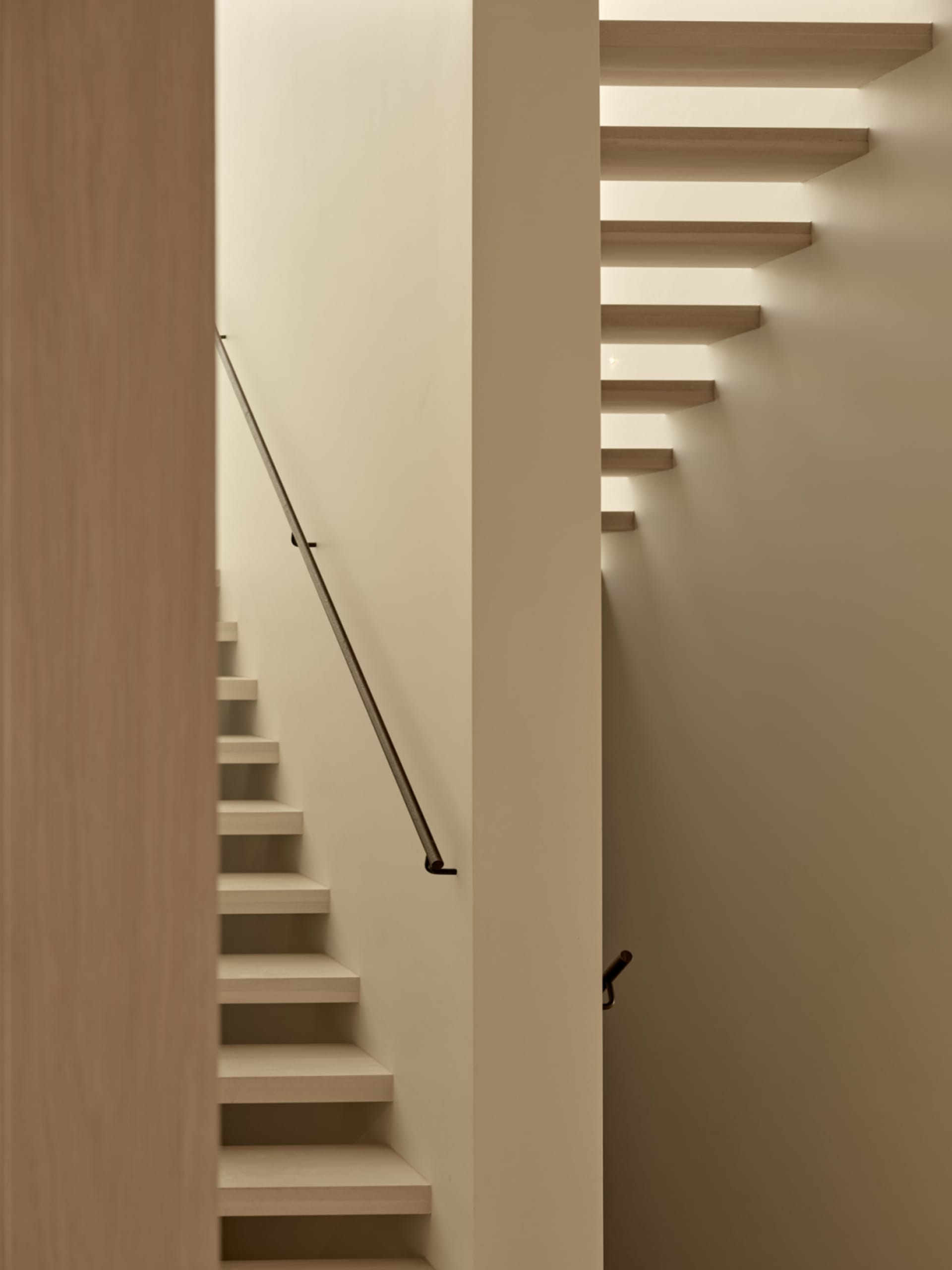 A narrow stairwell with wooden steps and a white color scheme, set against a blank background