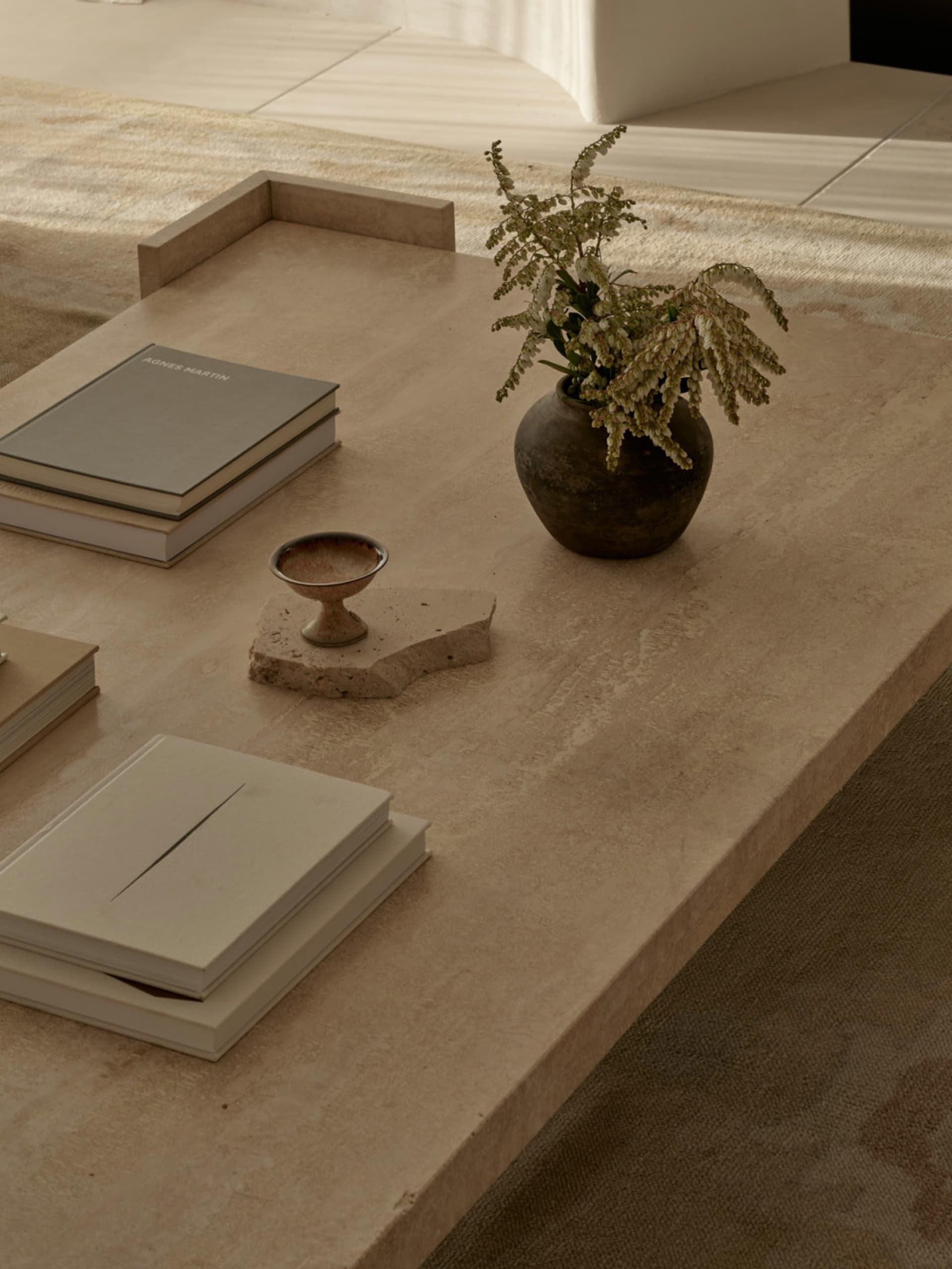 A cozy living area with a dining table, books, and a vase with flowers, creating a warm and inviting atmosphere