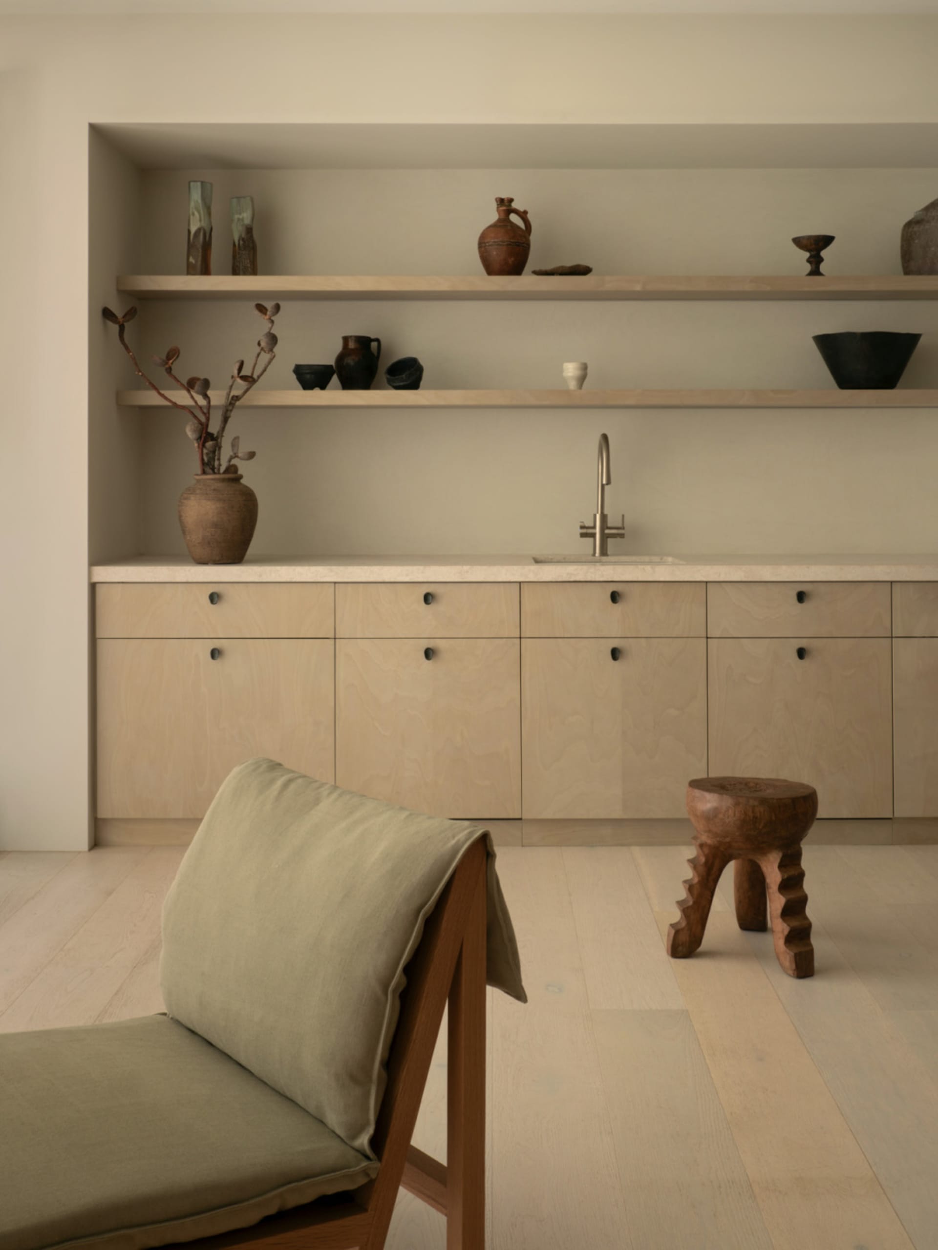 Modern kitchen with white walls, wooden floors, and decorative vases, featuring a sink and wooden cabinets