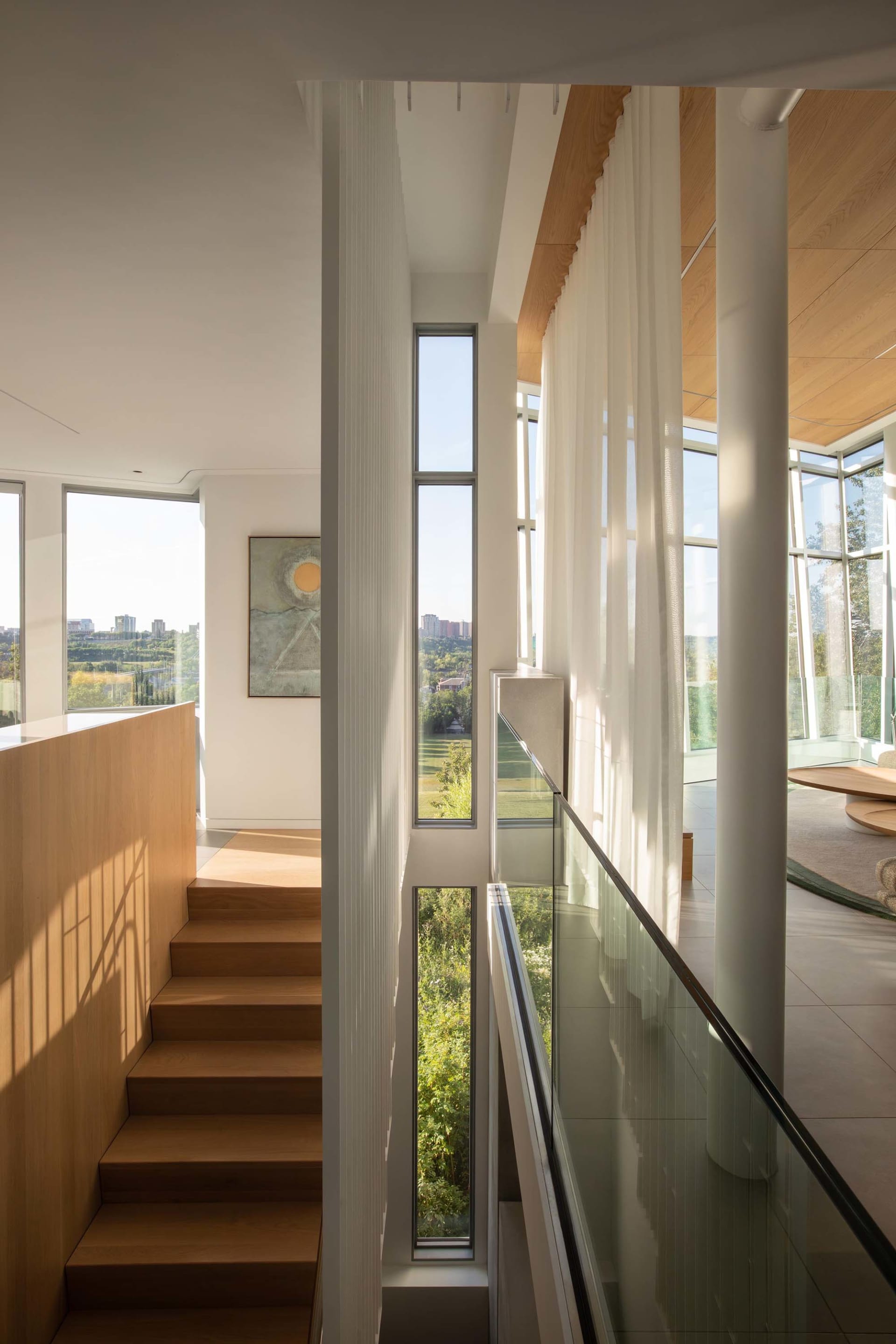A bright and inviting home with a wooden staircase, large windows, and a painting on the wall