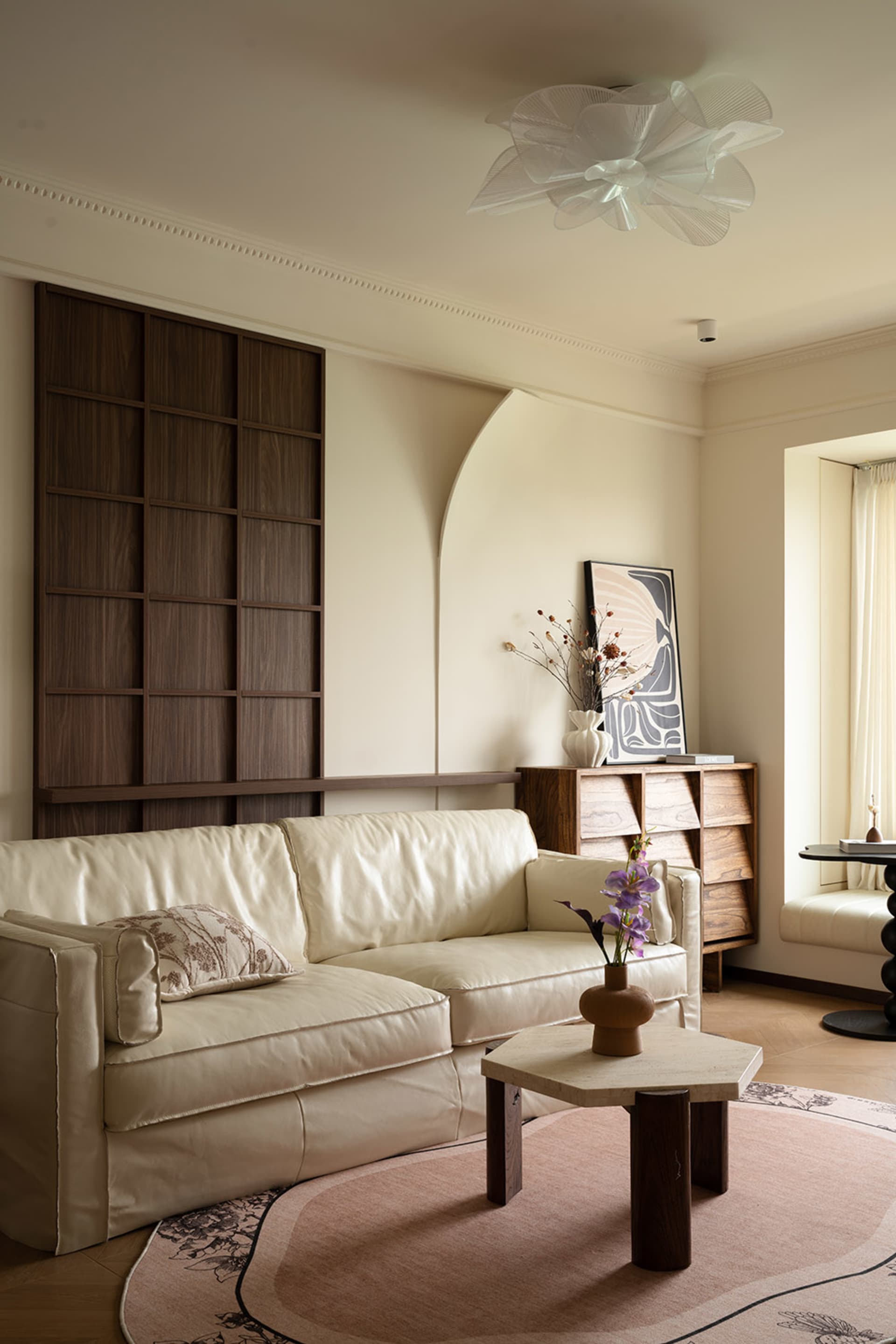A minimalist living room with white furniture, vases, and a potted plant, creating a clean and organized atmosphere