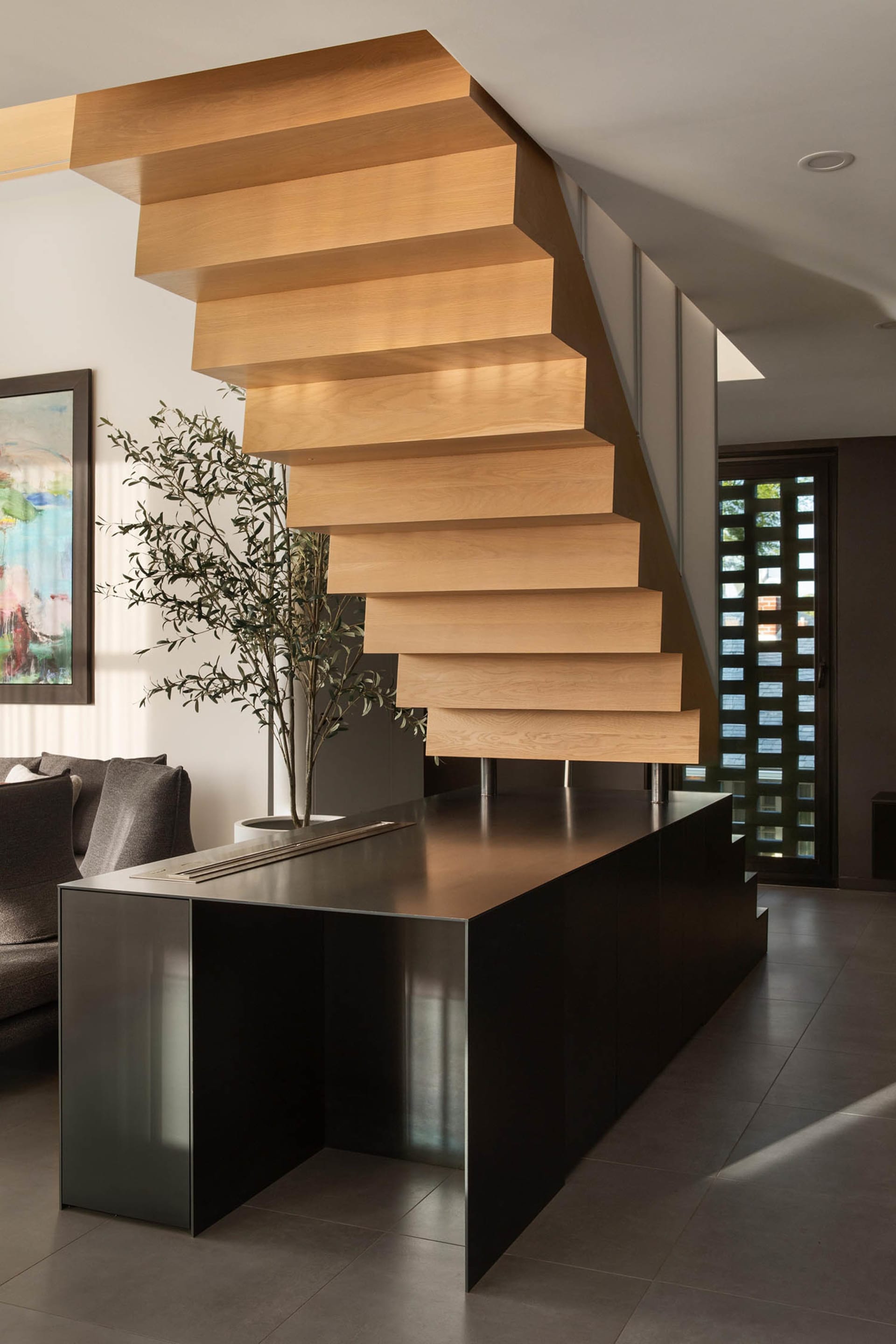 Cozy living space with a staircase featuring wooden steps, two couches, and a potted plant near the left couch