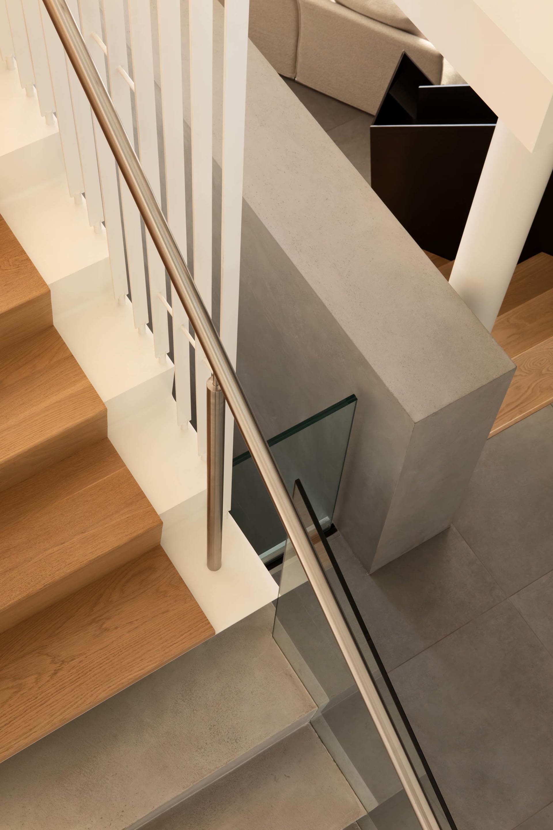 A wooden staircase with a metal railing in a well-lit, warm, and inviting living space with a residential feel