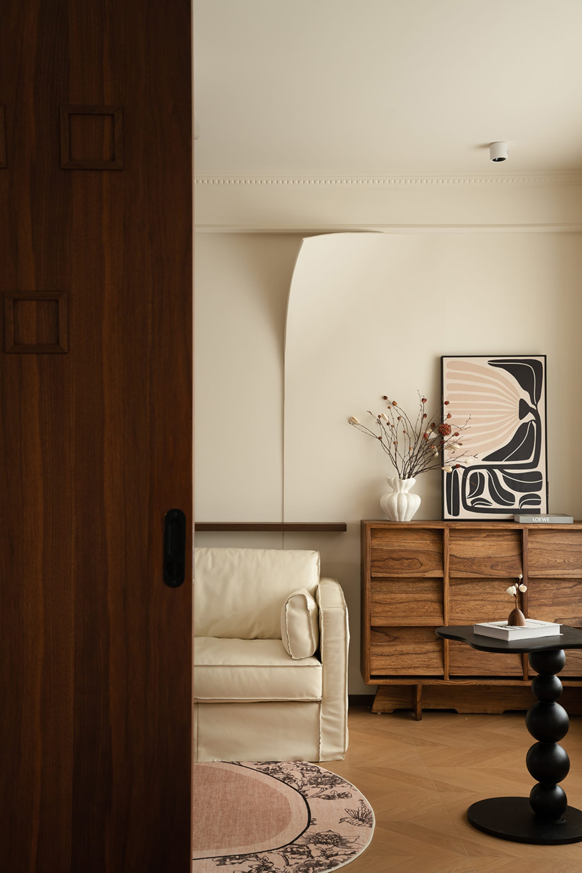 A well-lit living room with a couch near a doorway, featuring vases and a book on a table