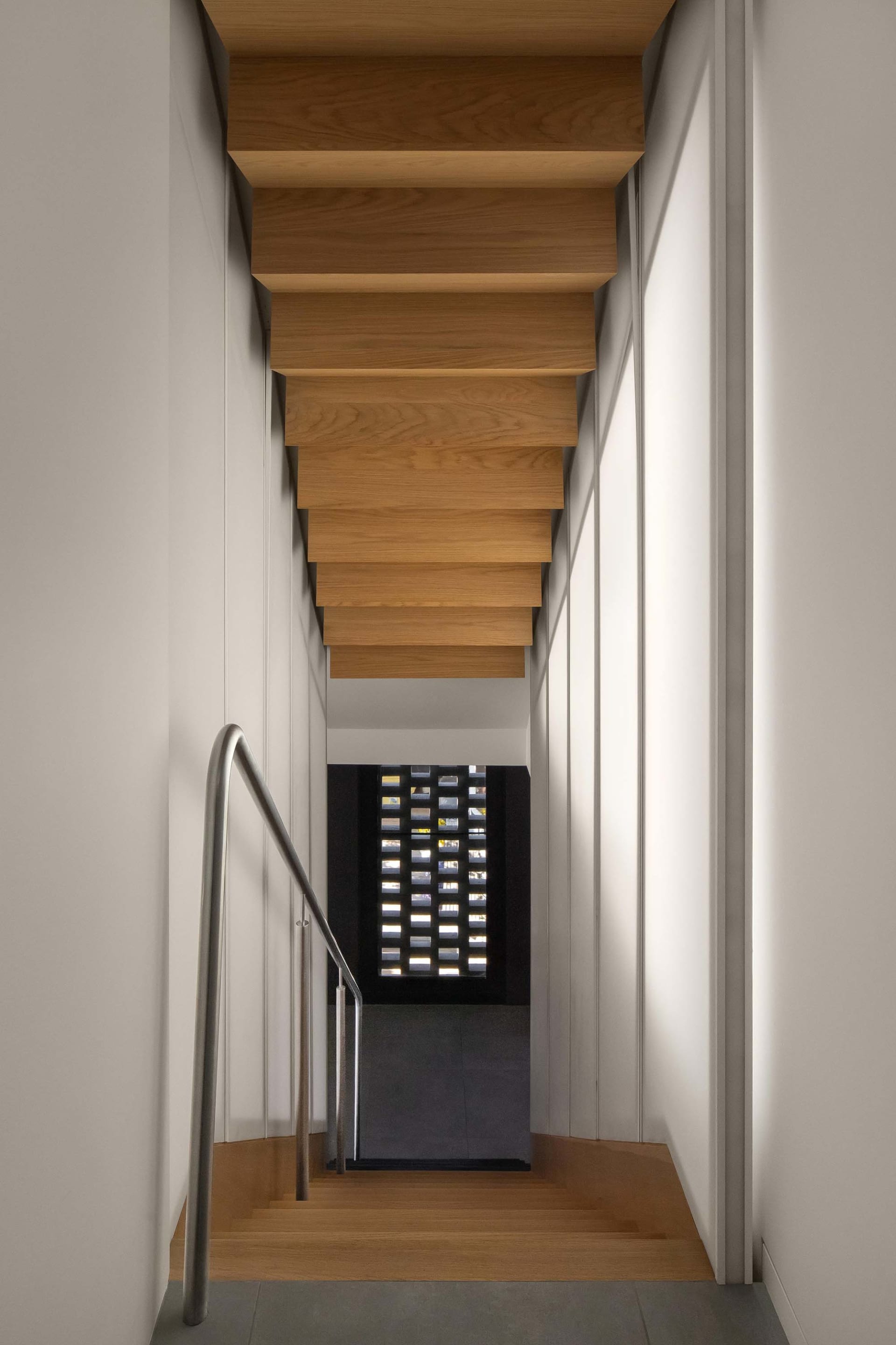 A well-designed staircase with wooden steps and a metal railing, leading to a room through a glass door