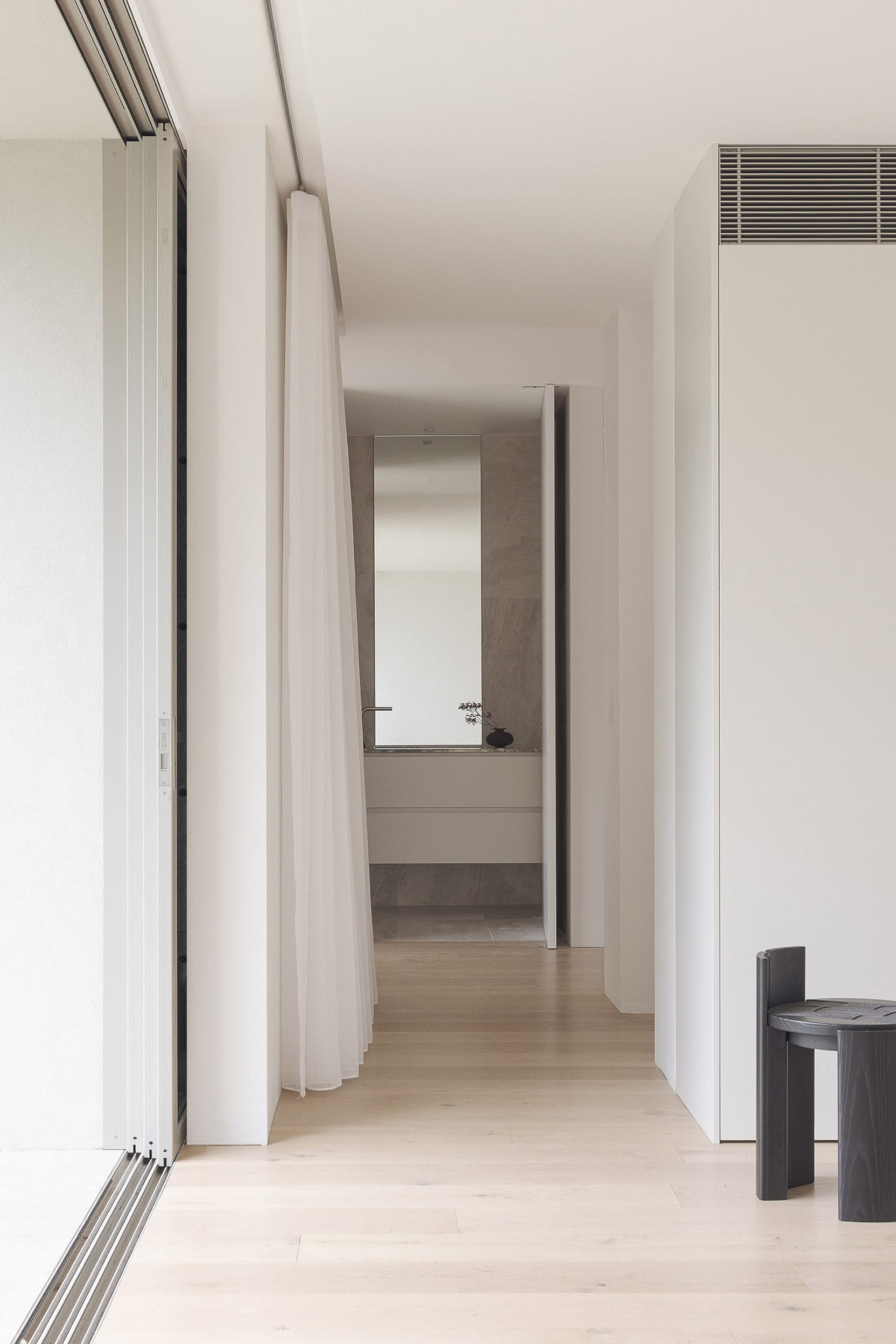 A clean and well-lit bathroom with two sinks, a bathtub, and wooden flooring