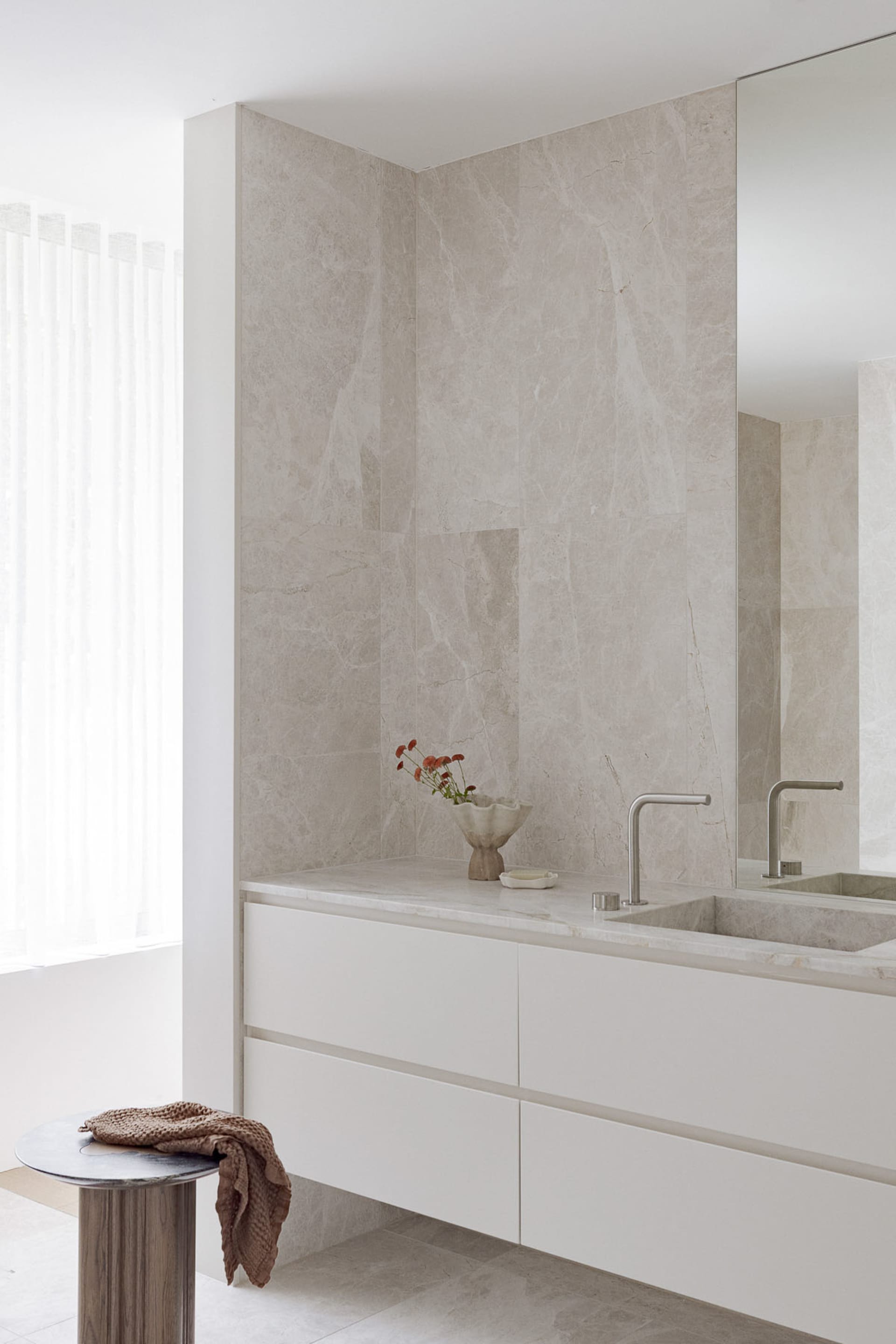 Bathroom with white marble walls and floors, two sinks, and marble countertops, conveying luxury and elegance