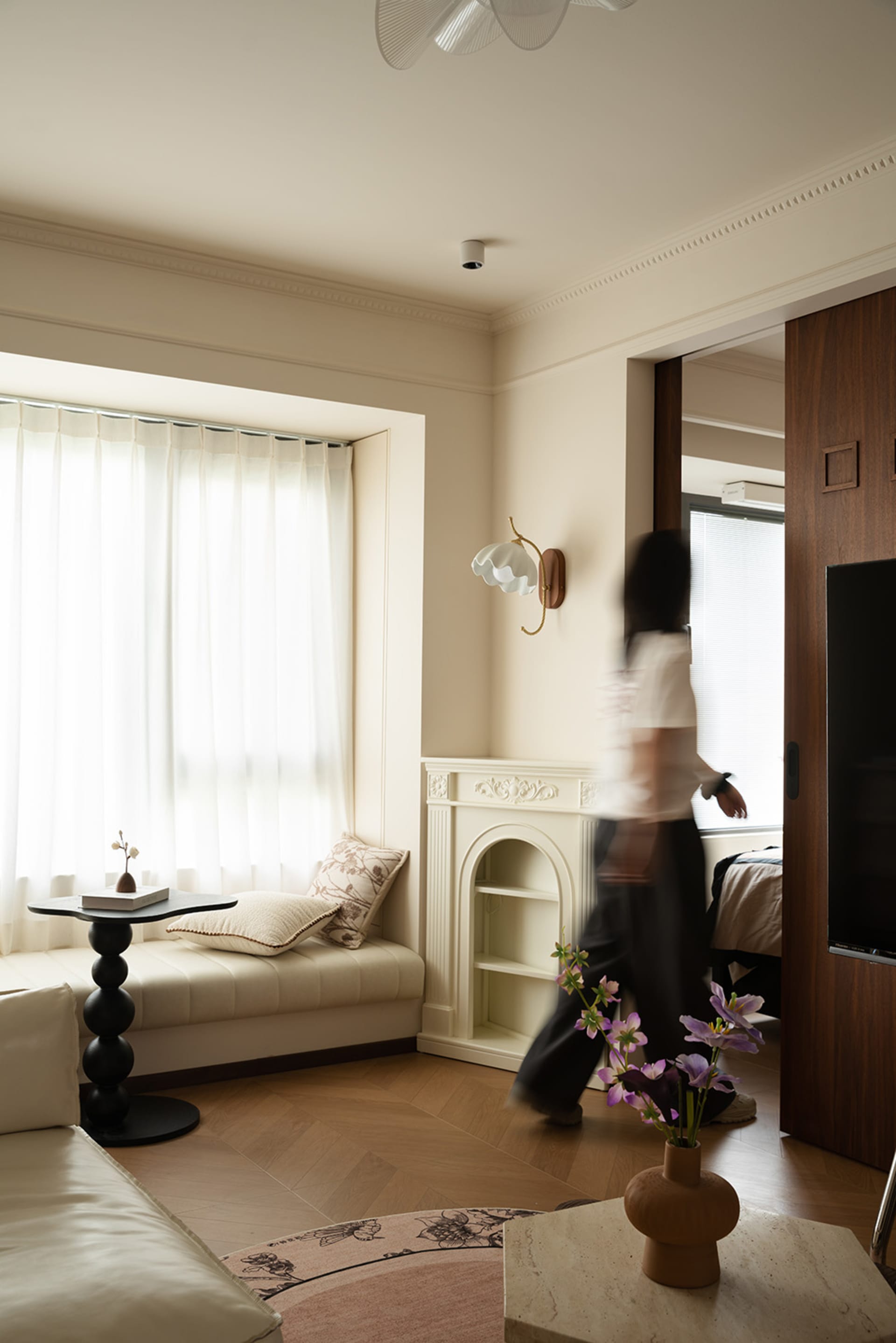 A cozy living space with two beds, a TV, a couch, a chair, a dining table, and potted plants