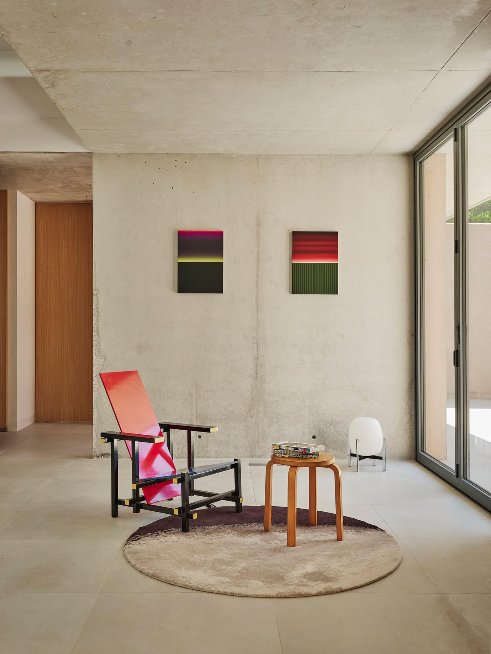 Cozy living space with a chair, table, and couch, featuring two wall-mounted pictures and a warm atmosphere