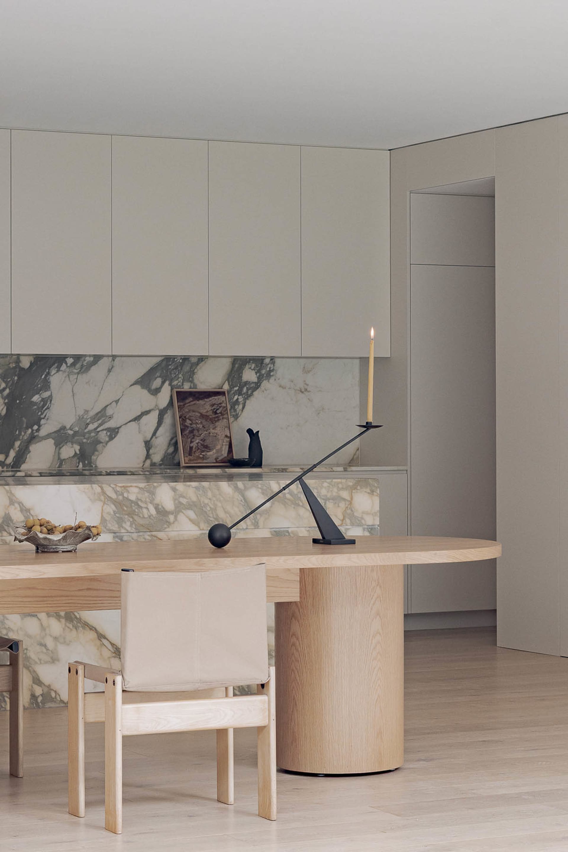 Warm and inviting modern kitchen with marble countertops, a wooden dining table, and white cabinets