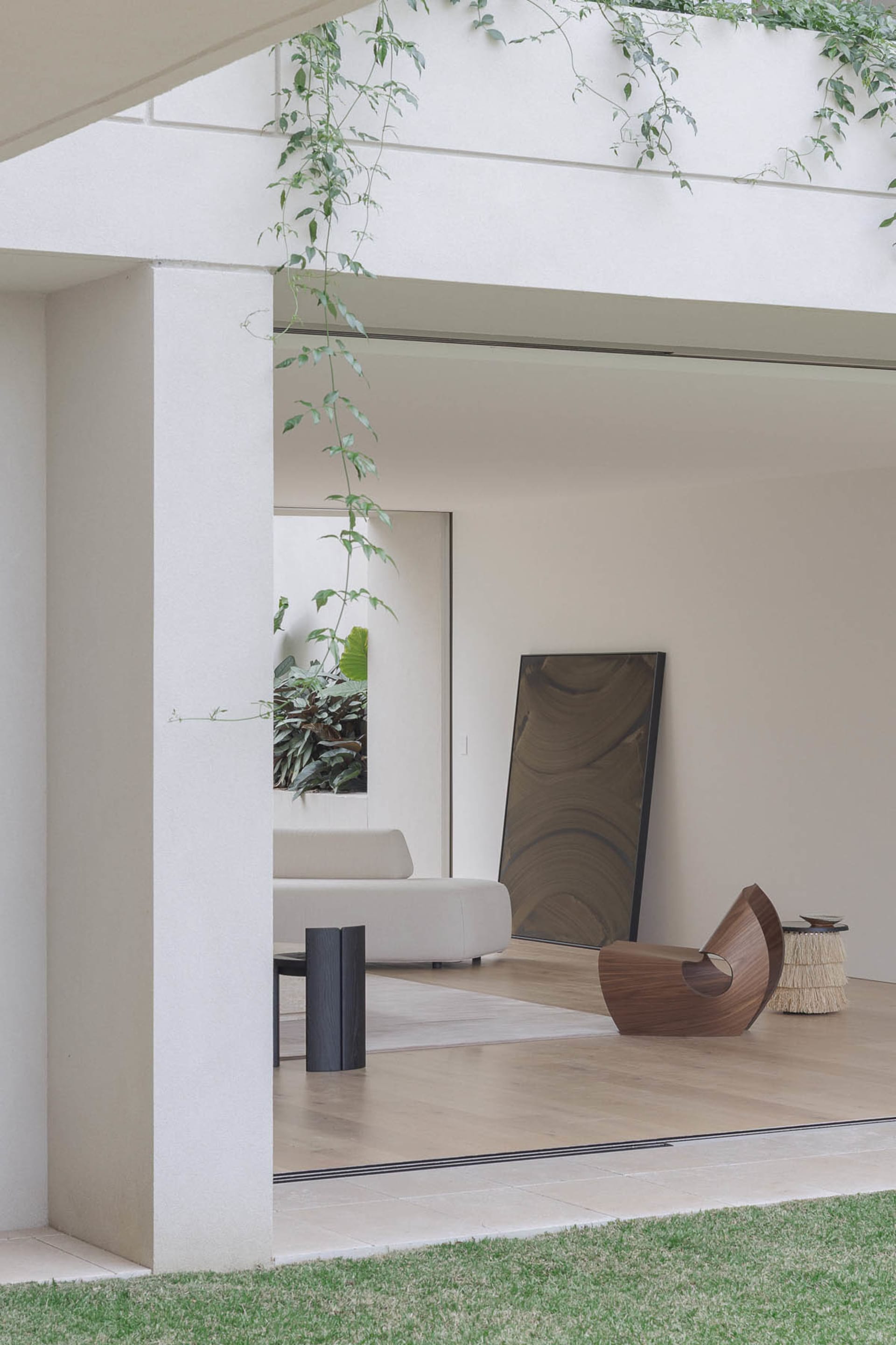 Open living area with white walls, two couches, a chair, a dining table, and potted plants