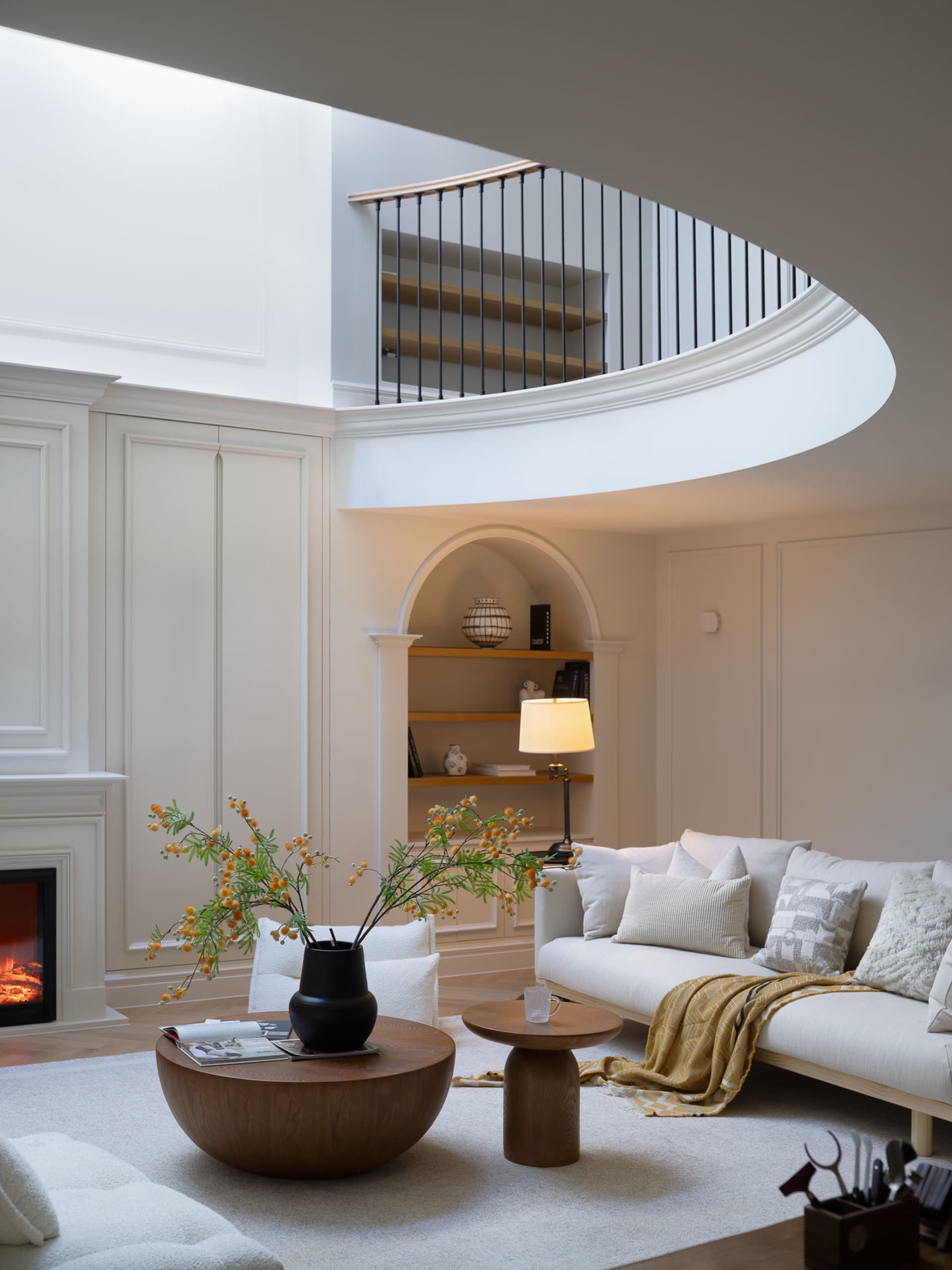Cozy living area with a white couch, two chairs, a coffee table, a potted plant, and a fireplace