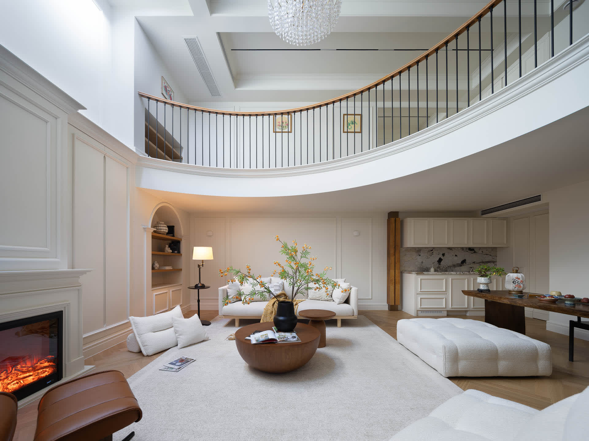 Open living area with a circular table, two couches, a dining table, and leather furniture in a modern space with white walls and wooden floors, filled with natural light