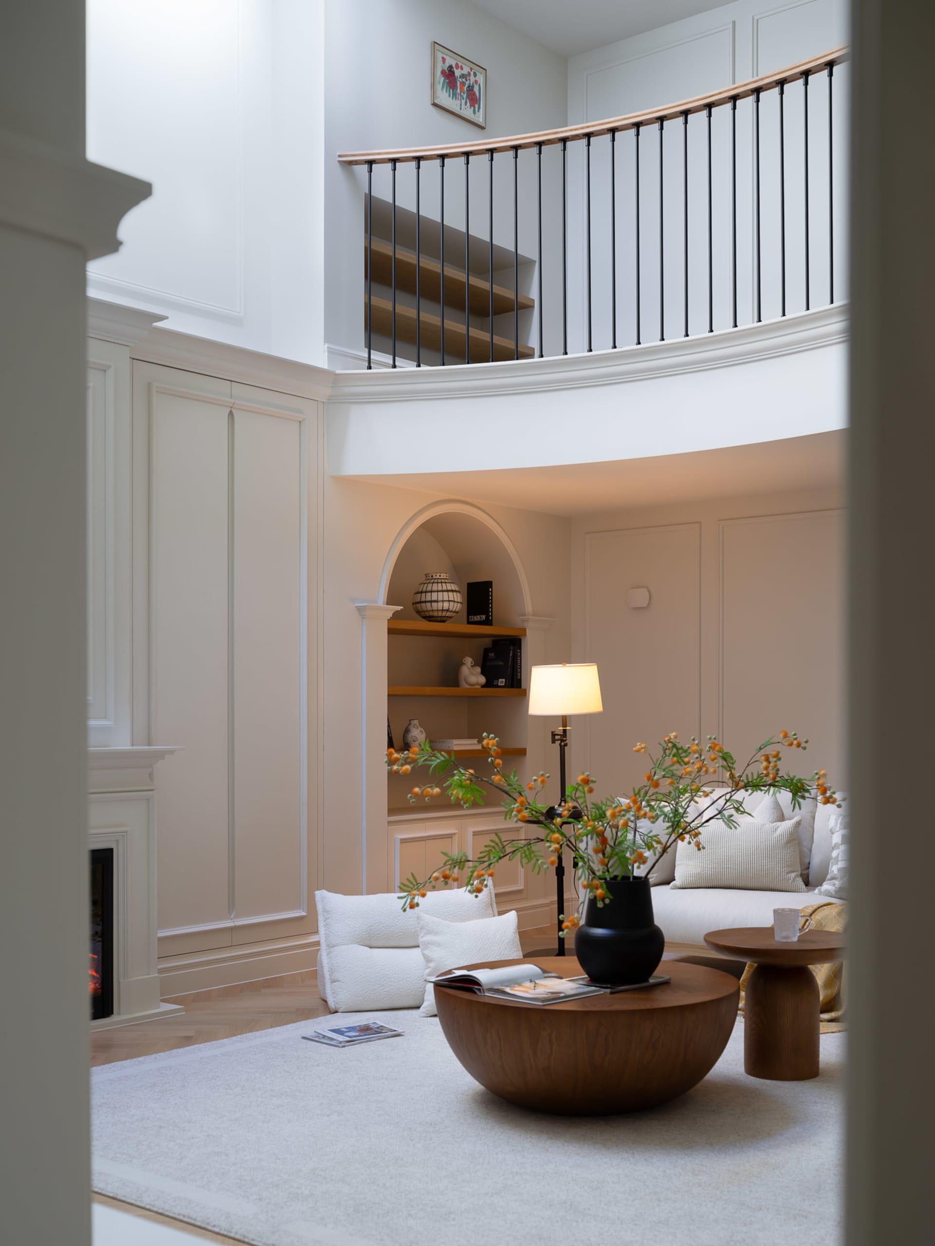A warm and inviting living area with a wooden table, white couches, and a potted plant, surrounded by books and comfortable seating