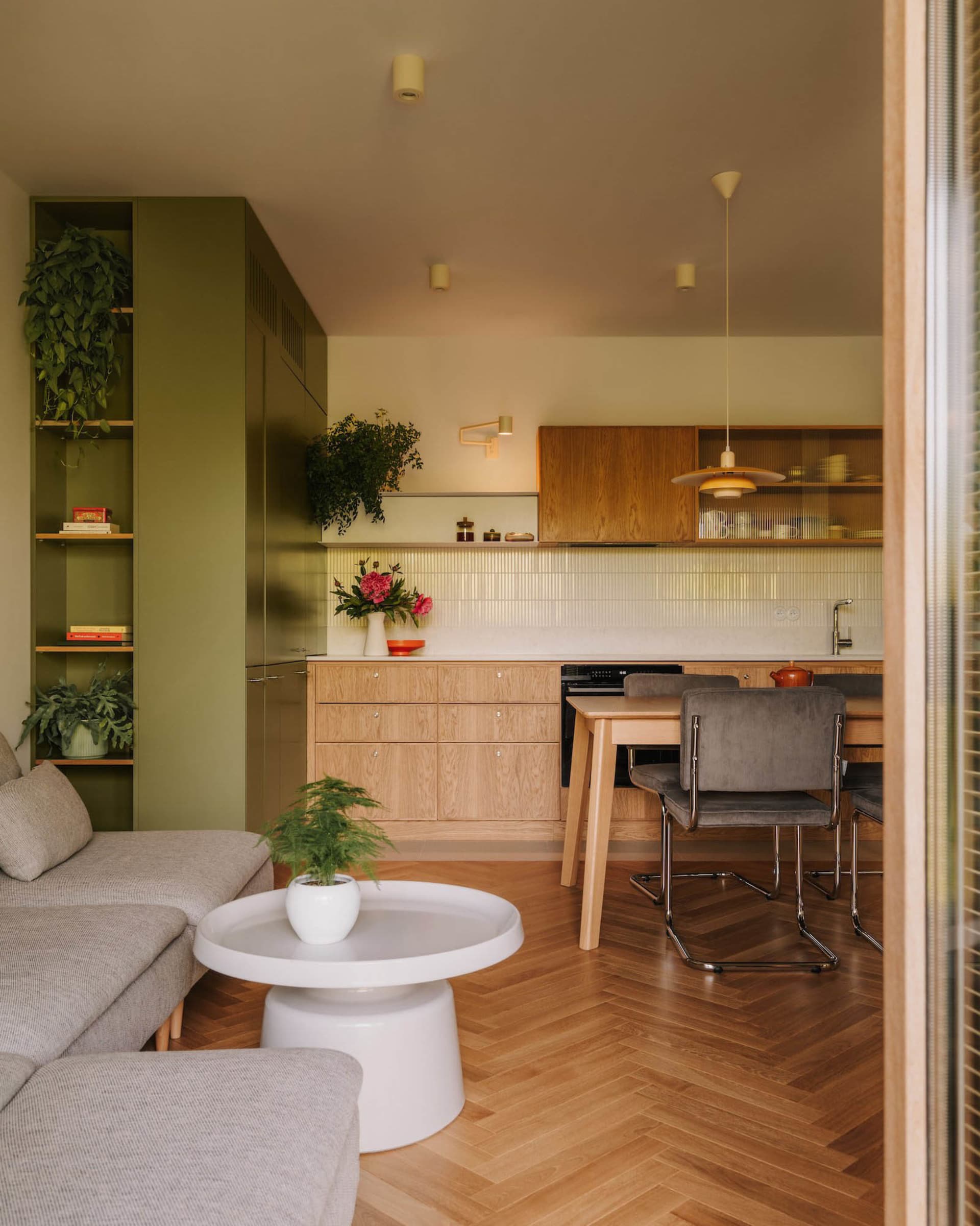Cozy open-plan kitchen and dining space with hardwood floors, white cabinets, green walls, and a lived-in feel