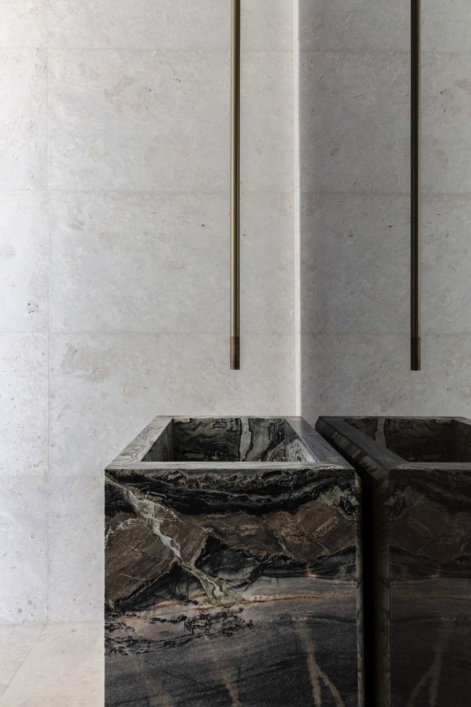 Bathroom with two black marble sinks, marble countertops, and a luxurious design