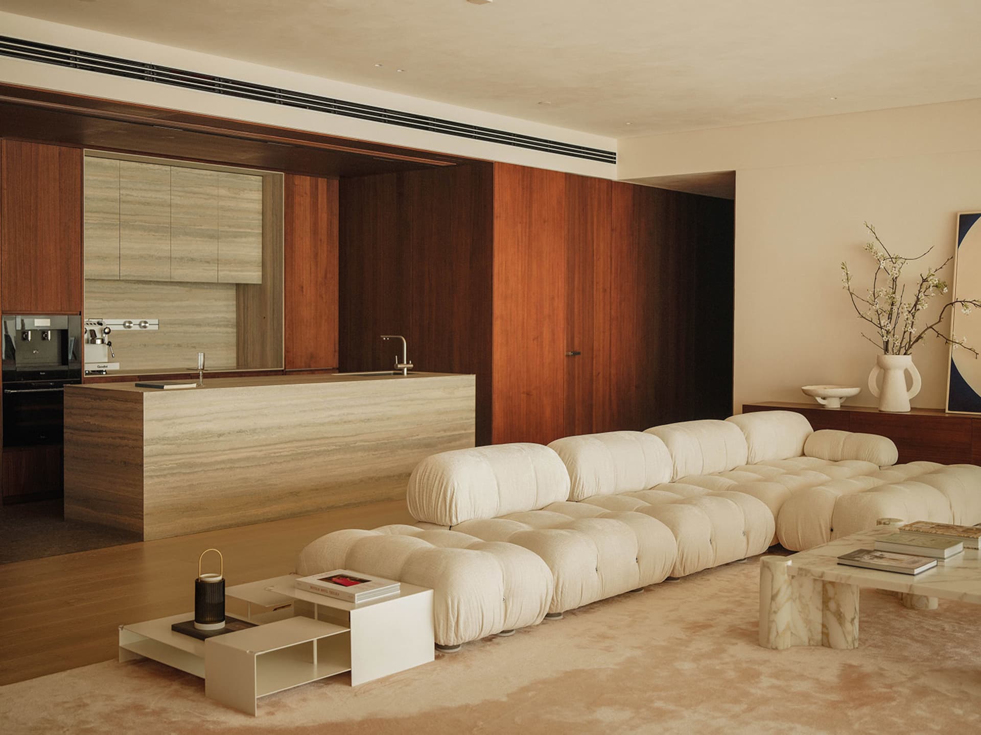 Open modern living space with a white couch, two sinks, and wooden walls, featuring clean lines and simplicity