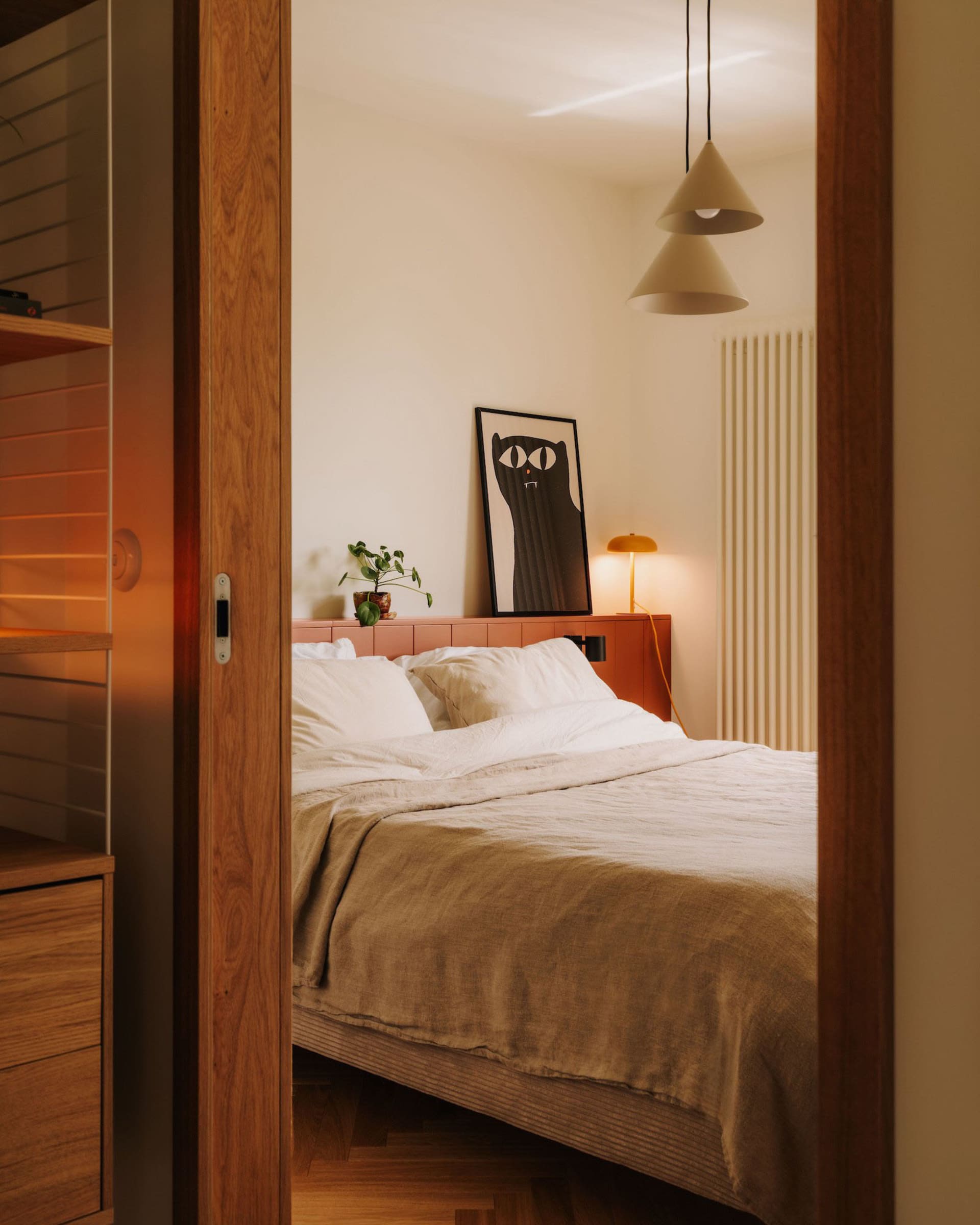 Cozy bedroom with a large bed, two potted plants, and a vase, set against a neutral background