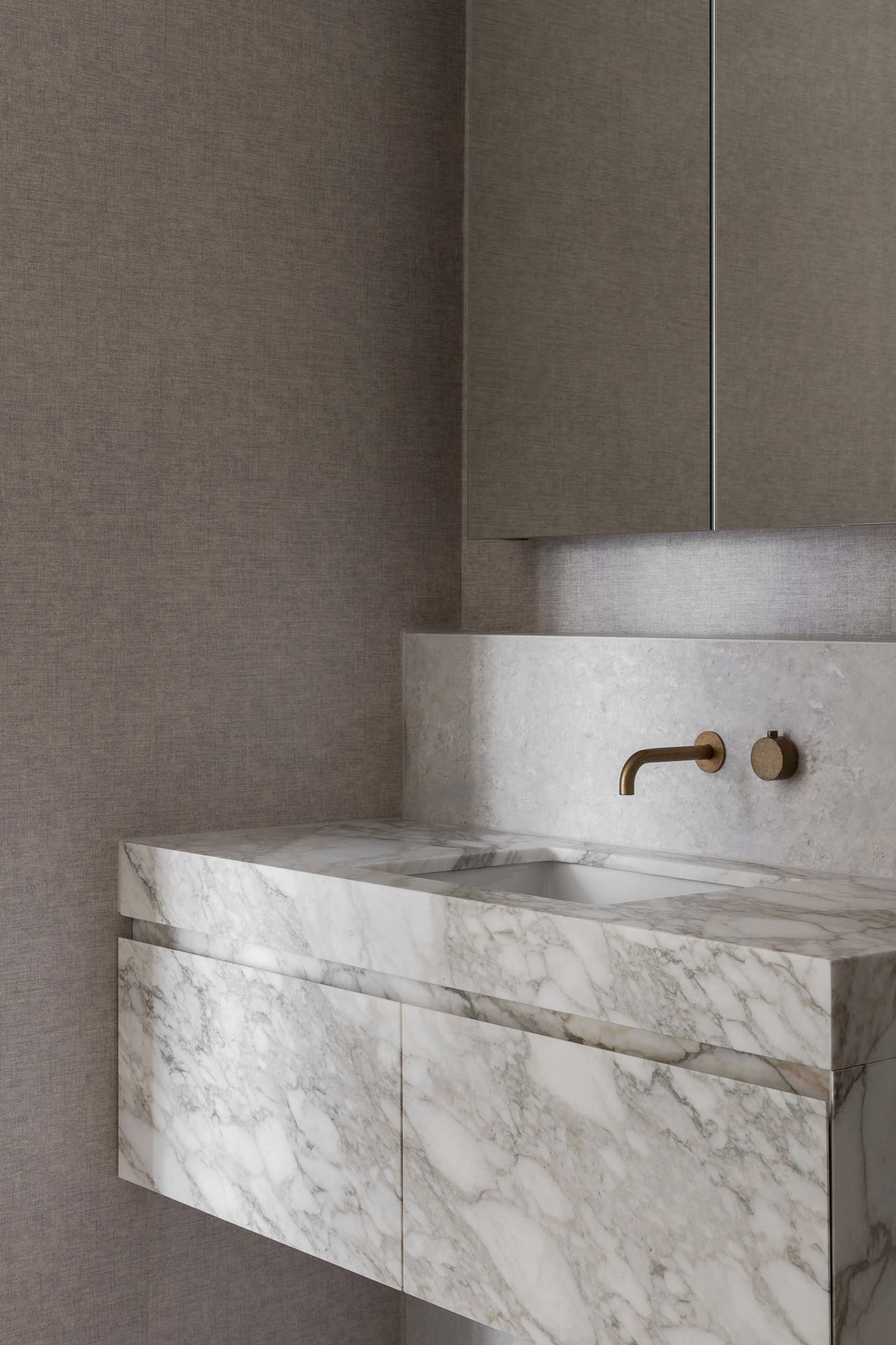 Modern bathroom with a marble countertop, sink, mirror, and cabinet, featuring a well-lit and elegant design