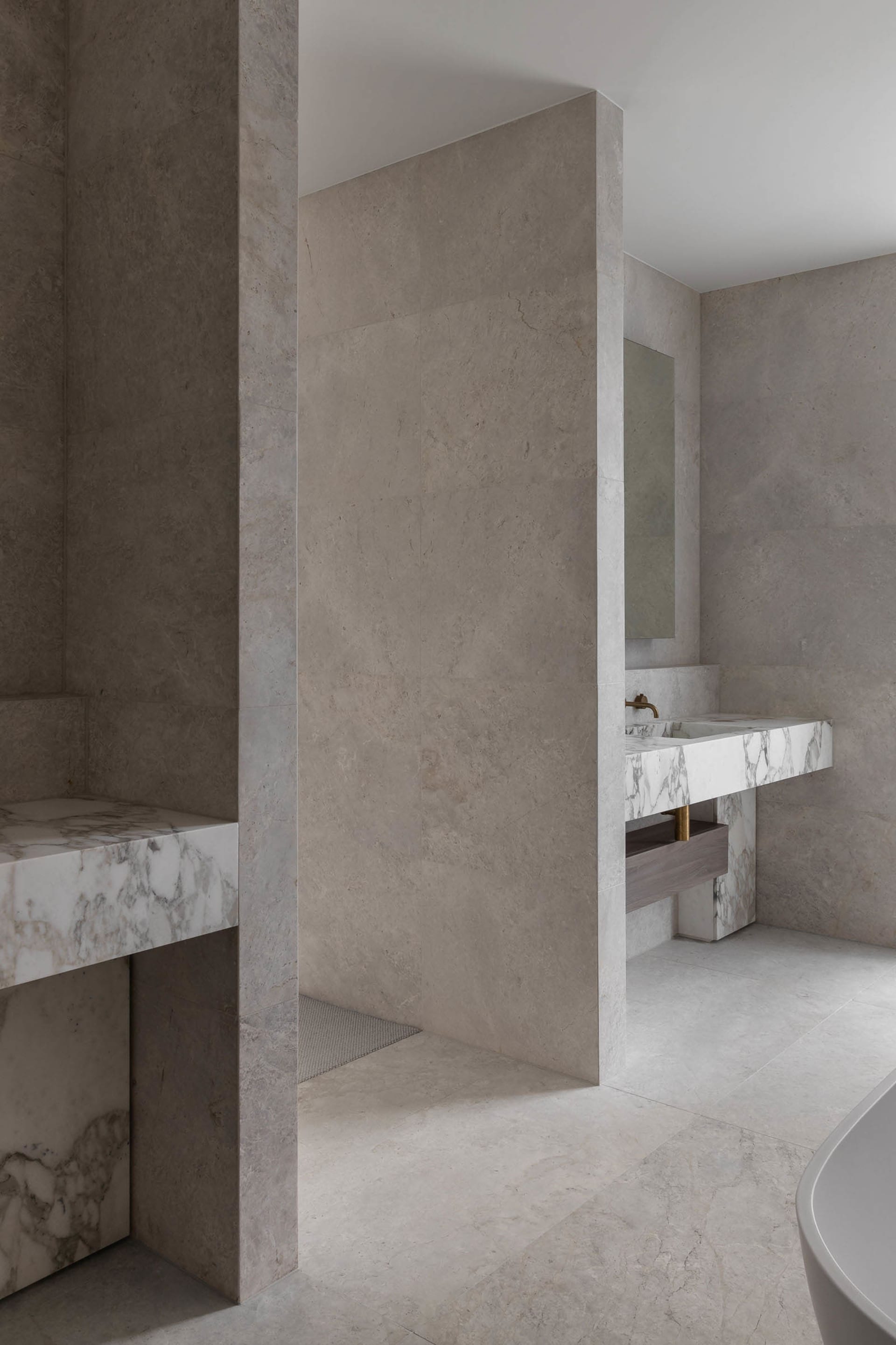 Bathroom with two sinks on a marble countertop, stone walls, and well-lit and spacious design