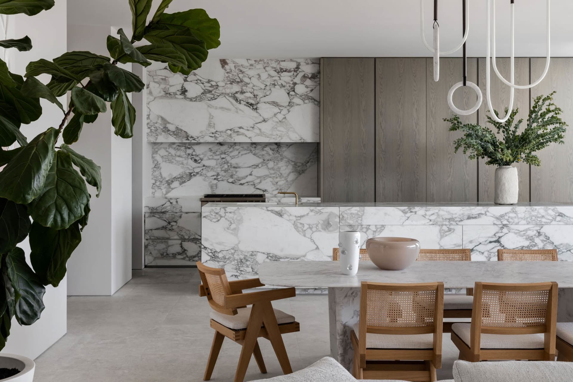 Open modern kitchen and dining space with marble countertops, wooden cabinets, and a comfortable seating area with a couch